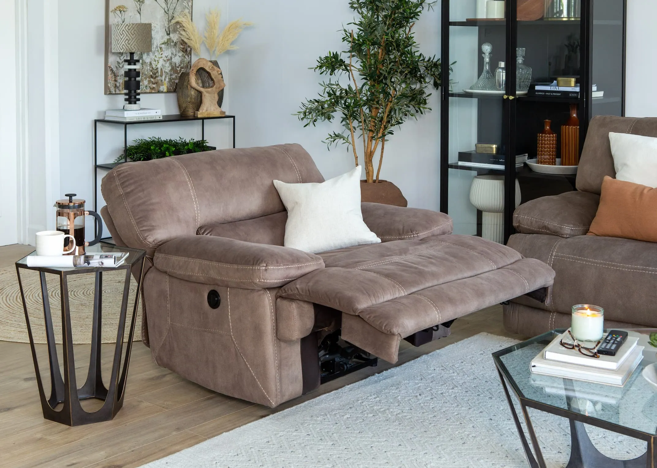 A lifestyle imange of the Baxter taupe recliner in recline mode with catalan tables and Tones of grey canvas.