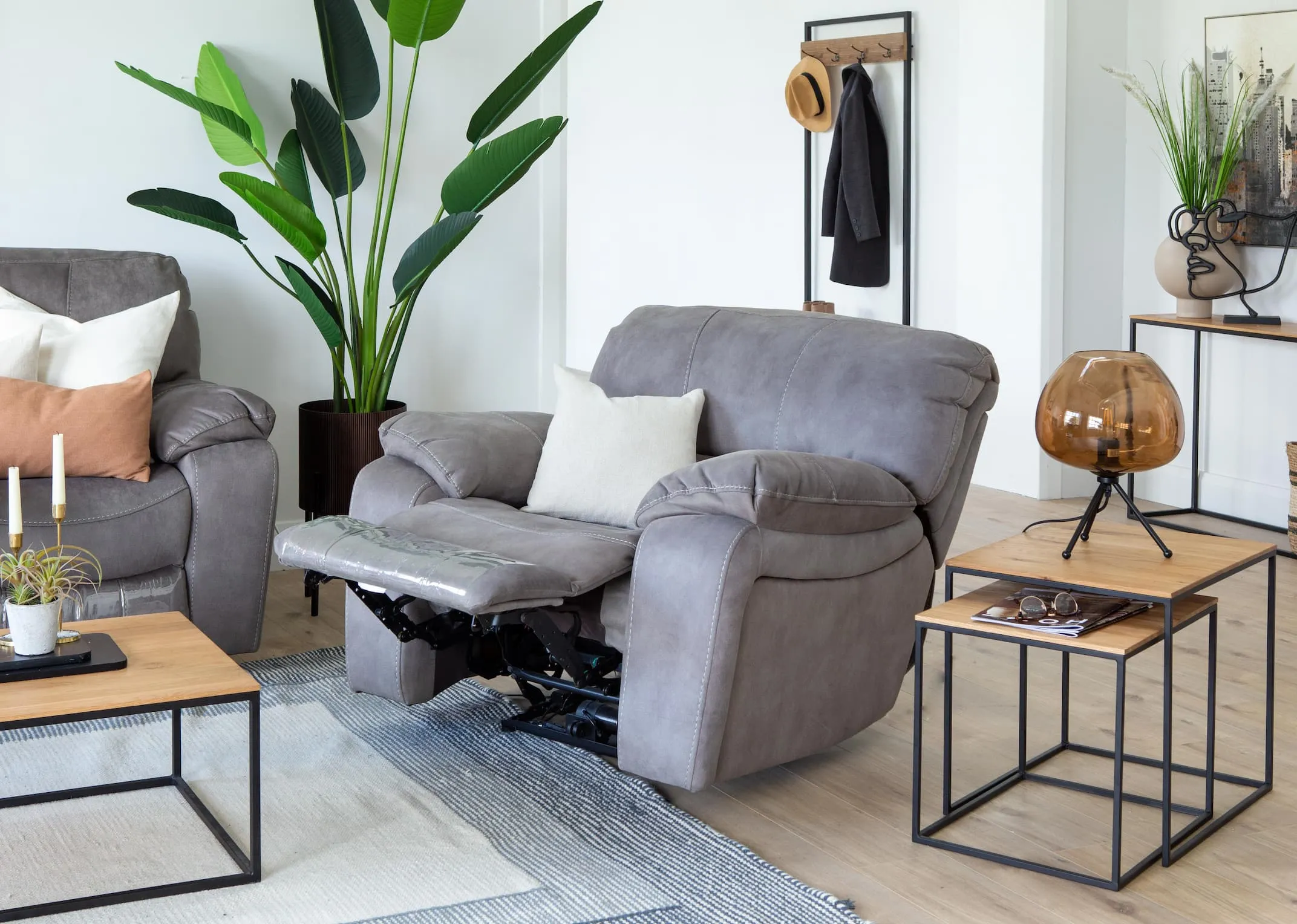 A lifestyle image of the Bradford grey armchair reclined with the Aston tables & Mellan floor lamp.