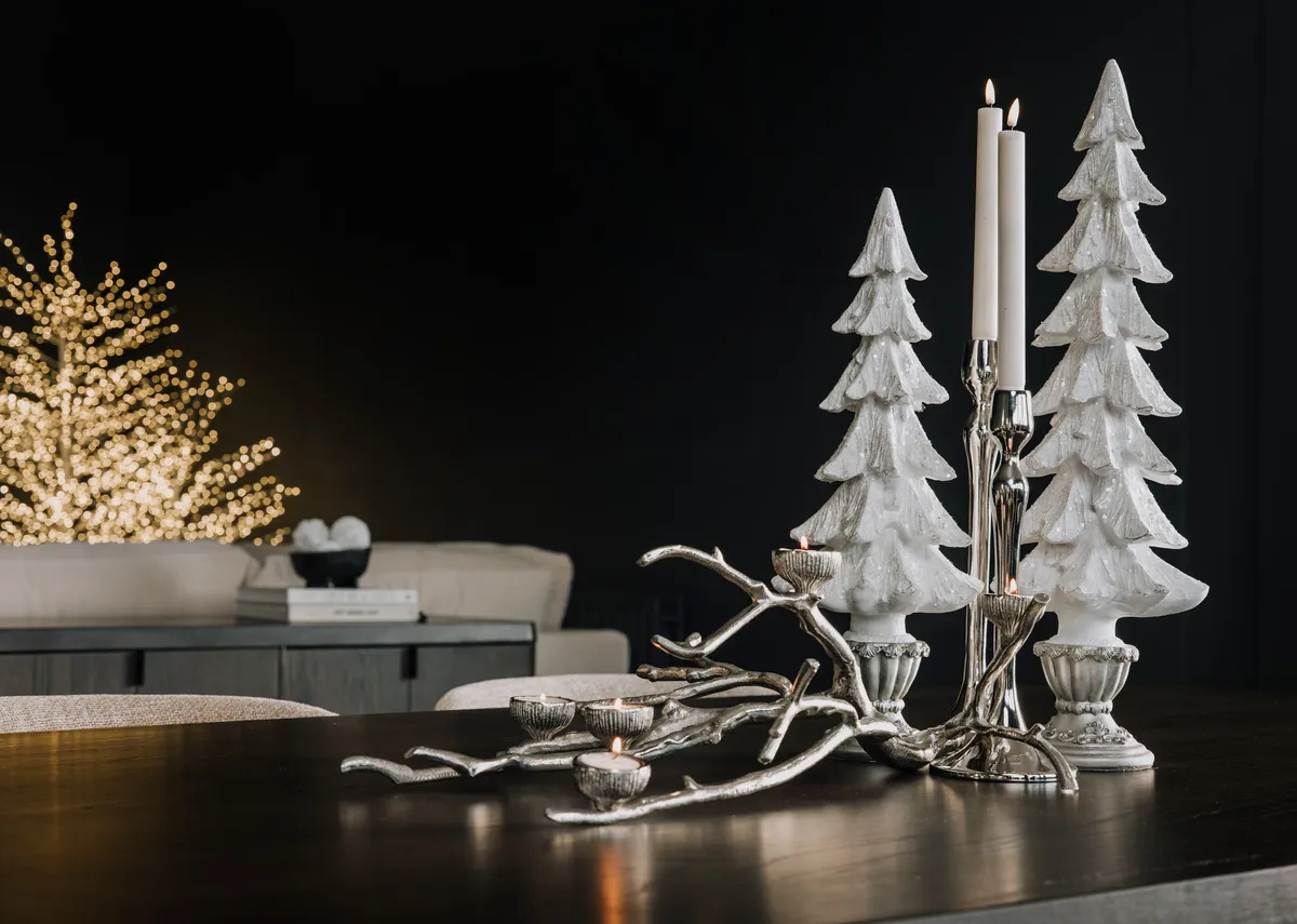 A lifestyle image of the Holly silver candleholders and White Christmas tree ornaments on Rimini table