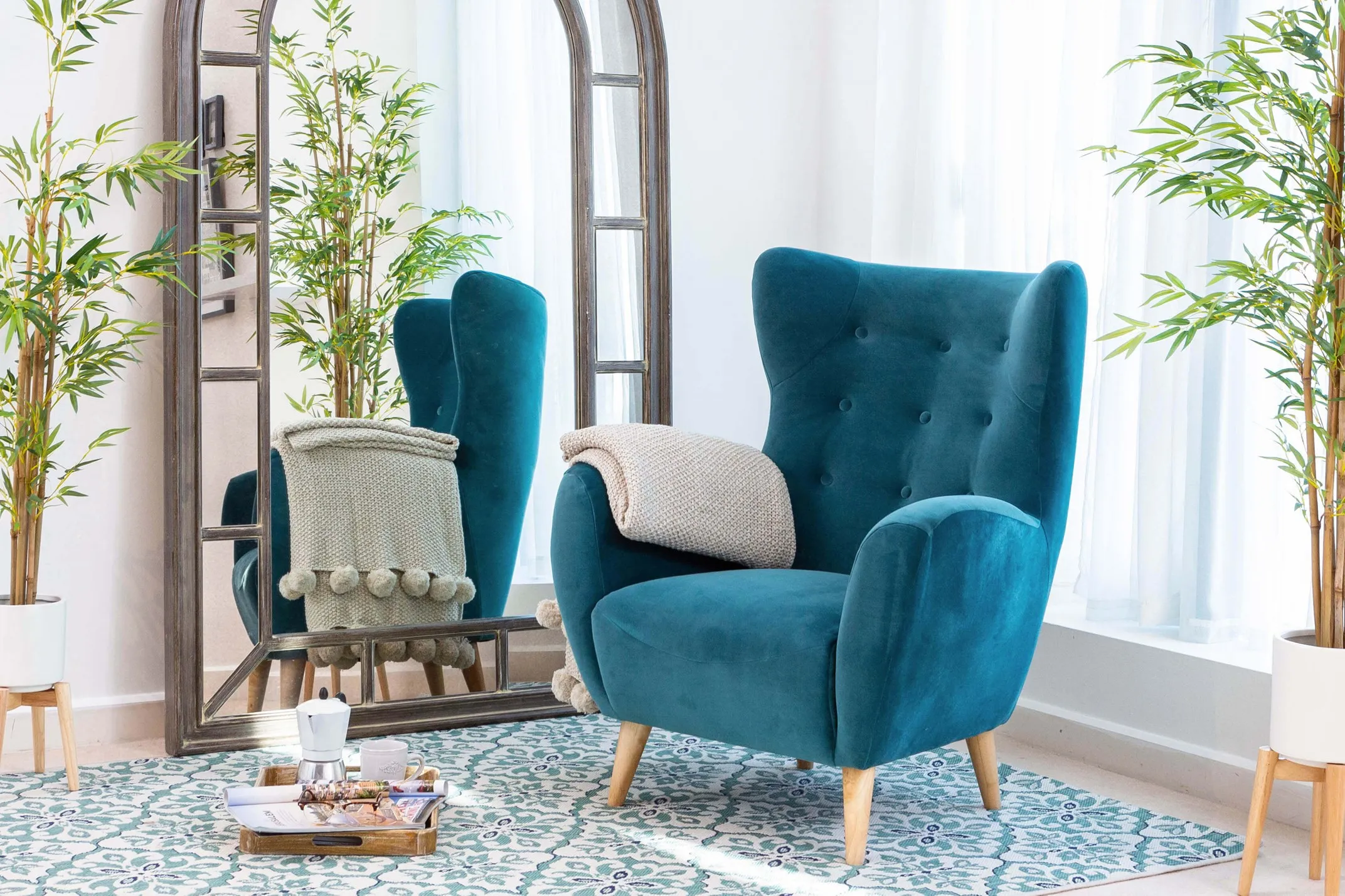 A lifestyle image showing the teal velvet Bronx armchair featuring the Tara rug
