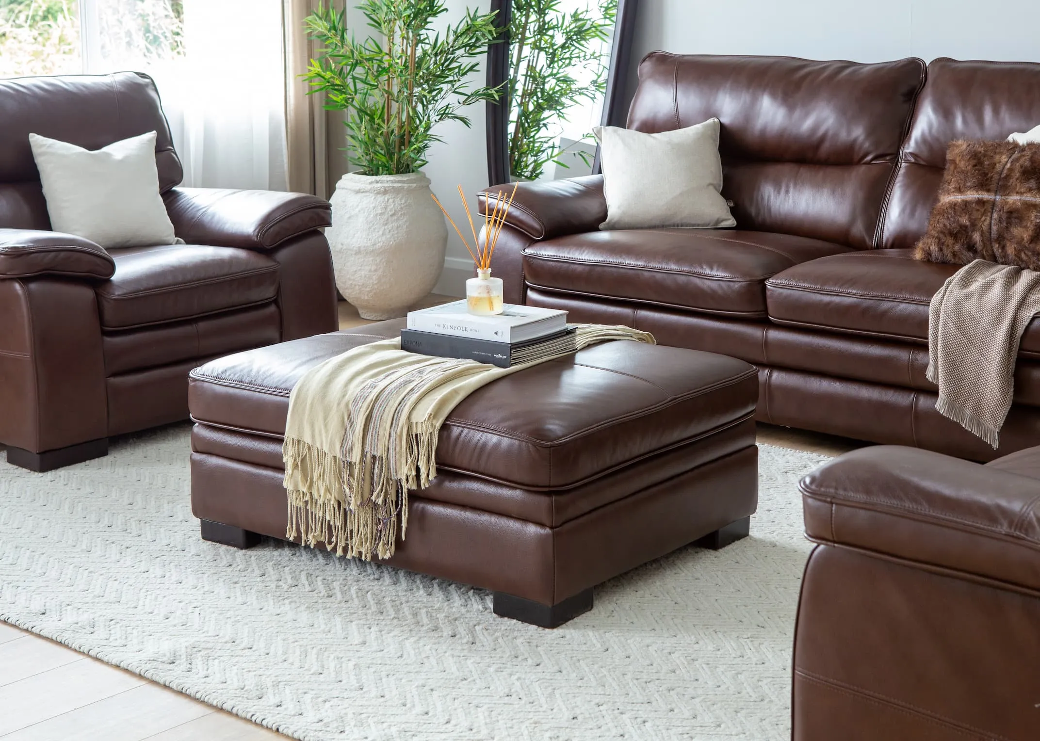 A lifestyle image of the Apollo Brown leather sofa set with the footstool