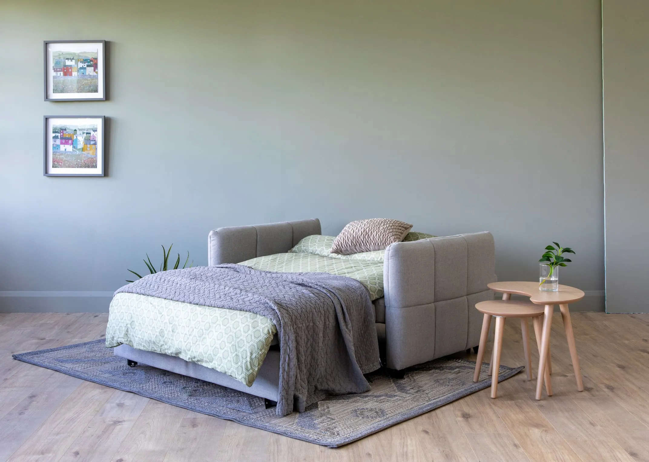 A lifestyle image of the Celeste Sofa dresses as a bed with dansk tables & 2 sister house prints.