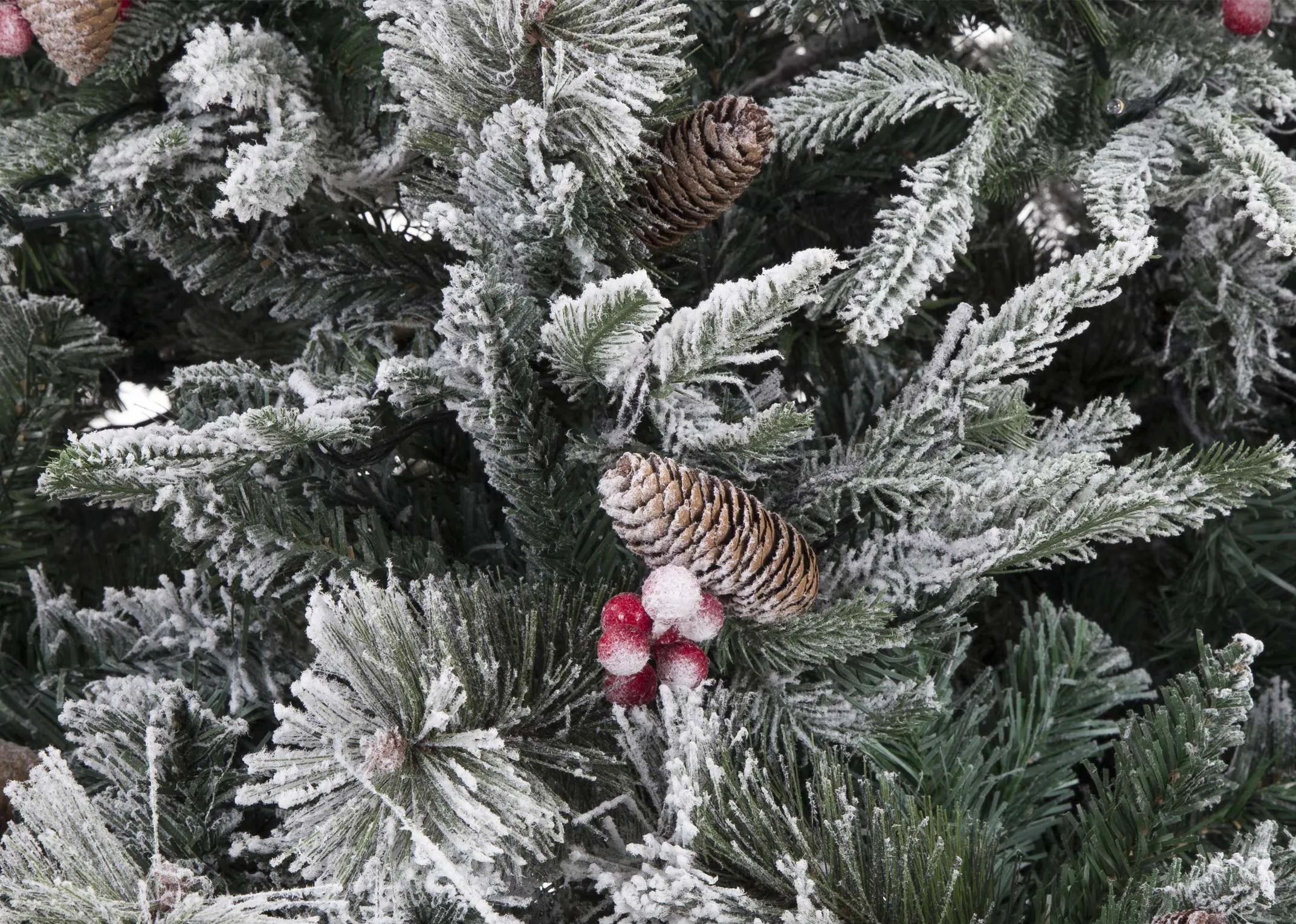 A closeup view of an 8 foot xmas tree with snow covered branches berries and acorns.
