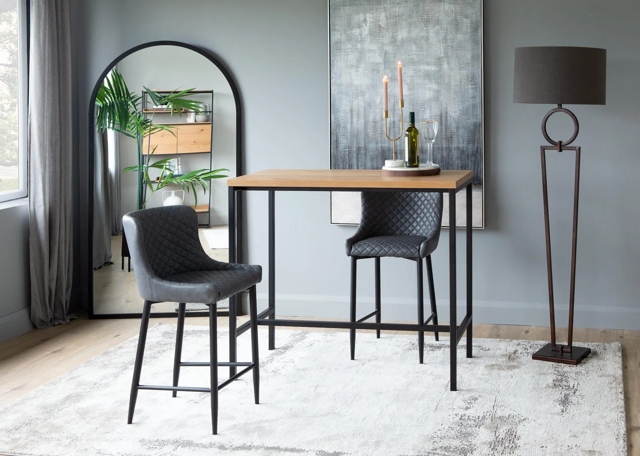 A lifestyle image of the Ottowa bar stools in grey faux leather with the rivoli bar table & chrisley mirror