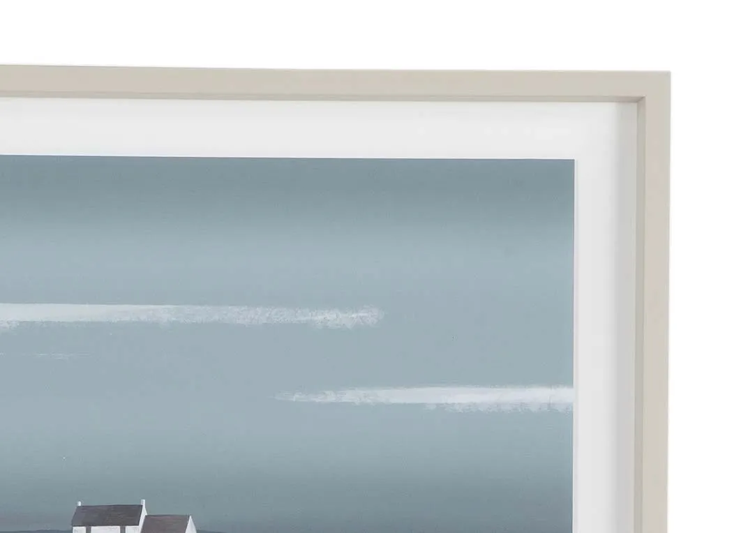 A beige framed print showing a coastal landscape from Ulyana Hammond. Closeup view.