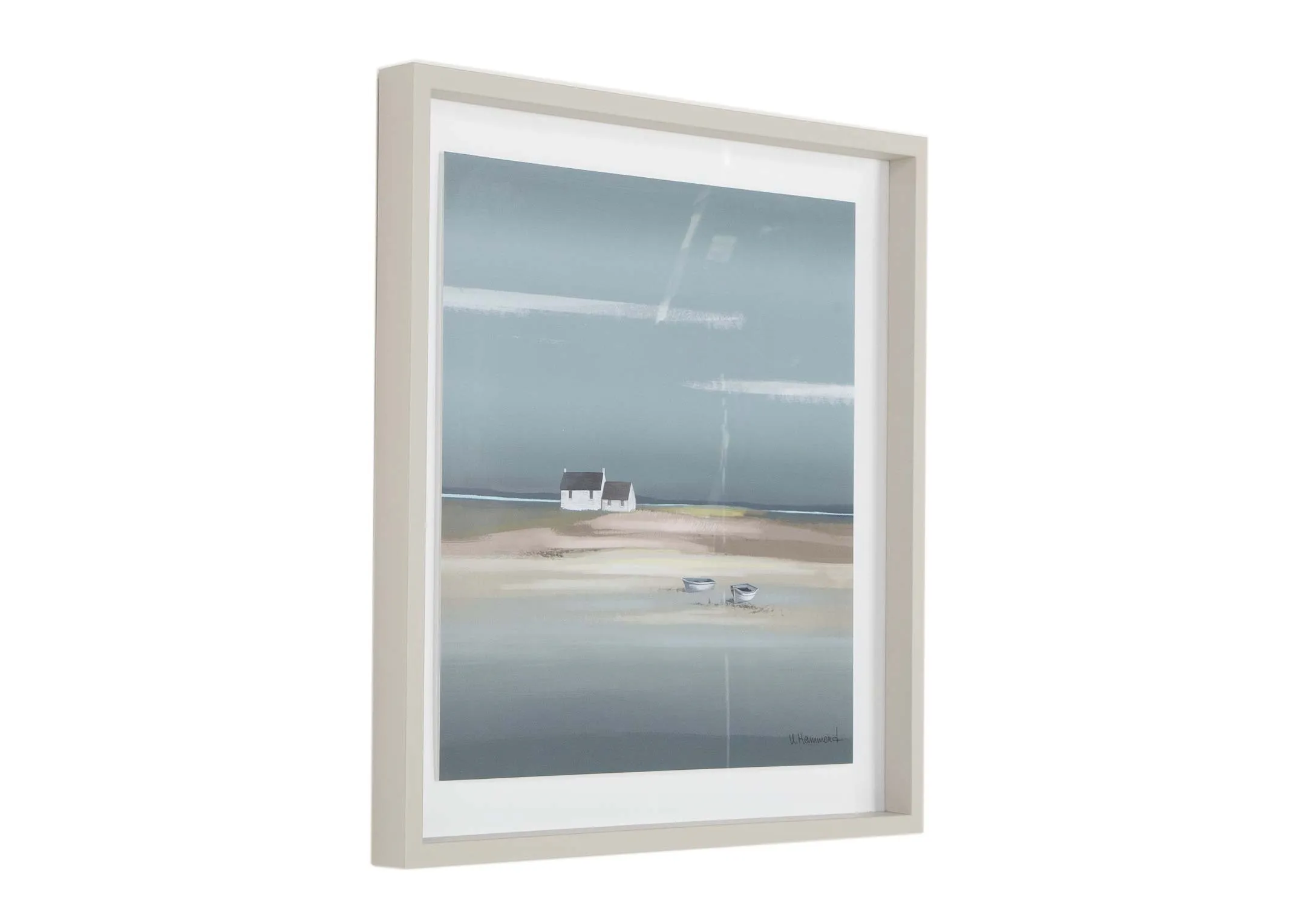 A beige framed print showing a coastal landscape from Ulyana Hammond. Angled view.
