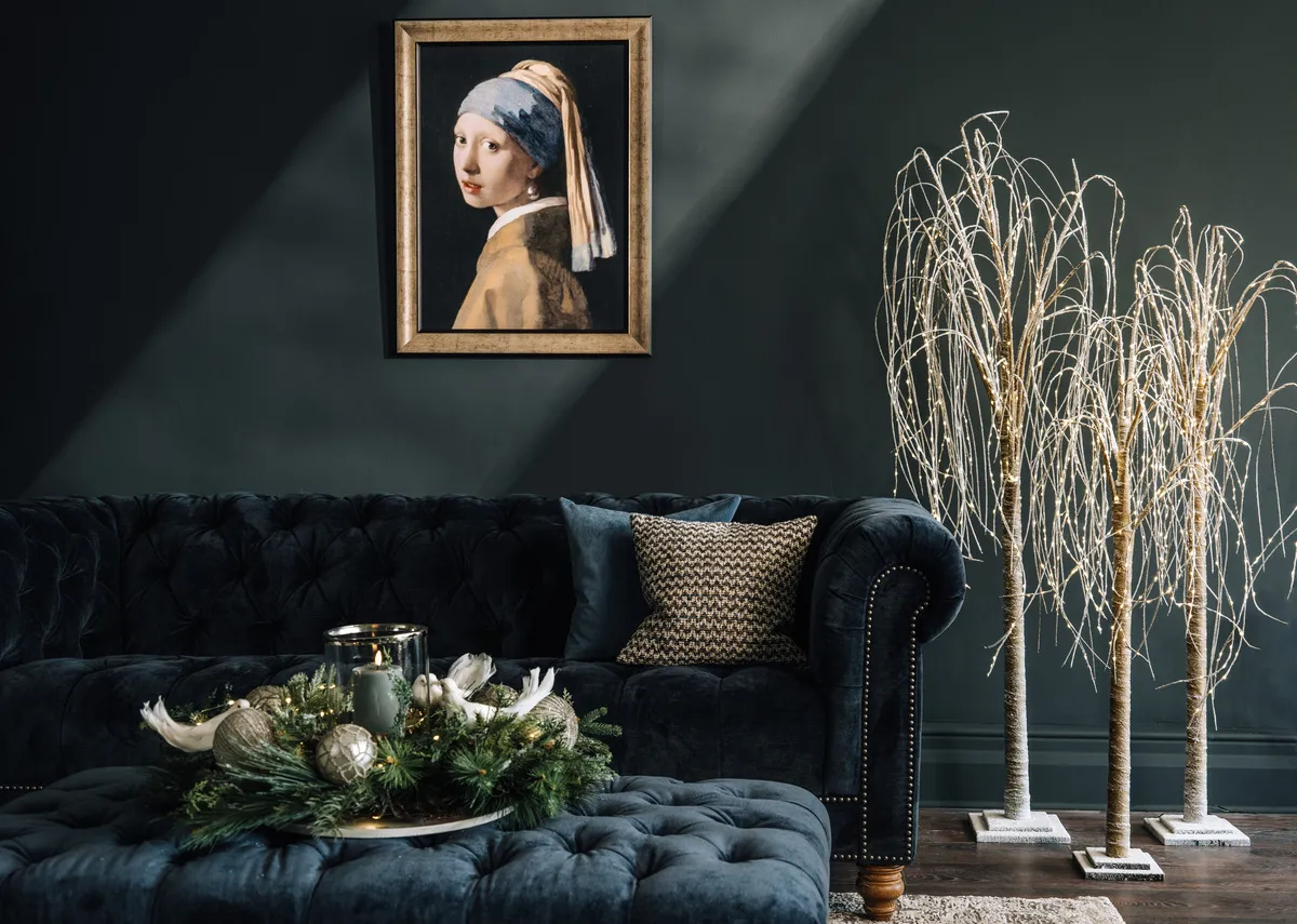 A lifestyle image of the Adare 3.5 seater in  navy velvet with Willow trees in all sizes and Girl with a Pearl earring picture