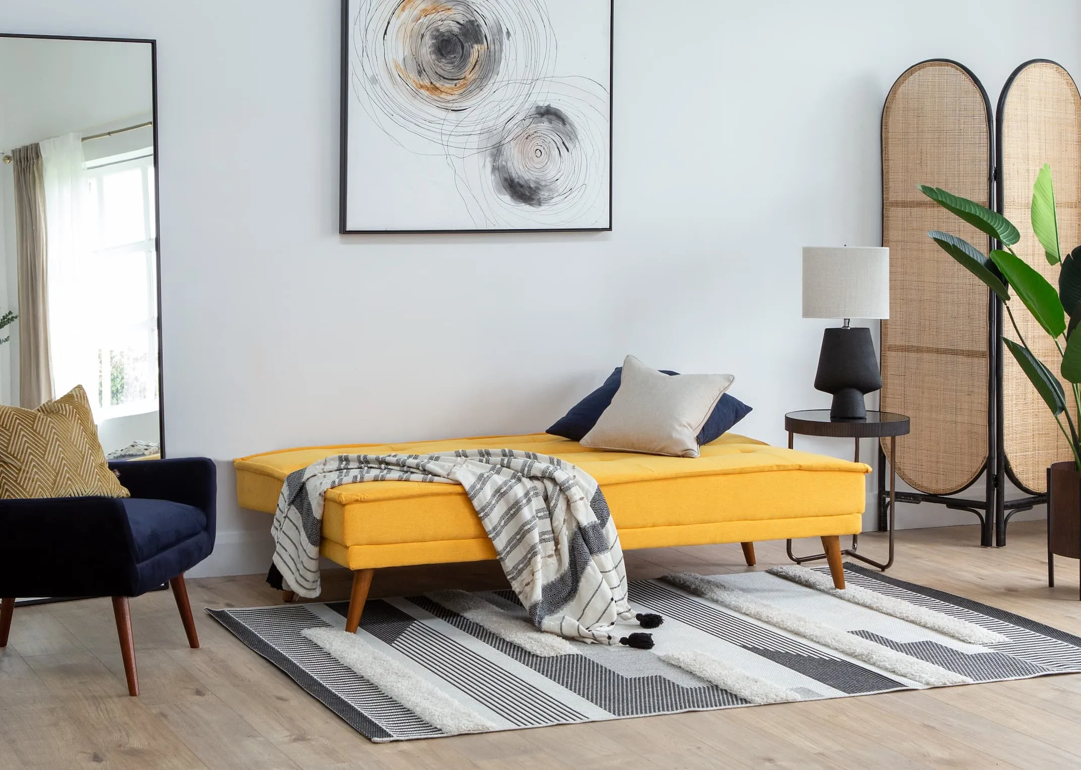 A lifestyle image of the Seattle yellow sofabed in bed mode with Janey chair & Circles print with Aztec rug.