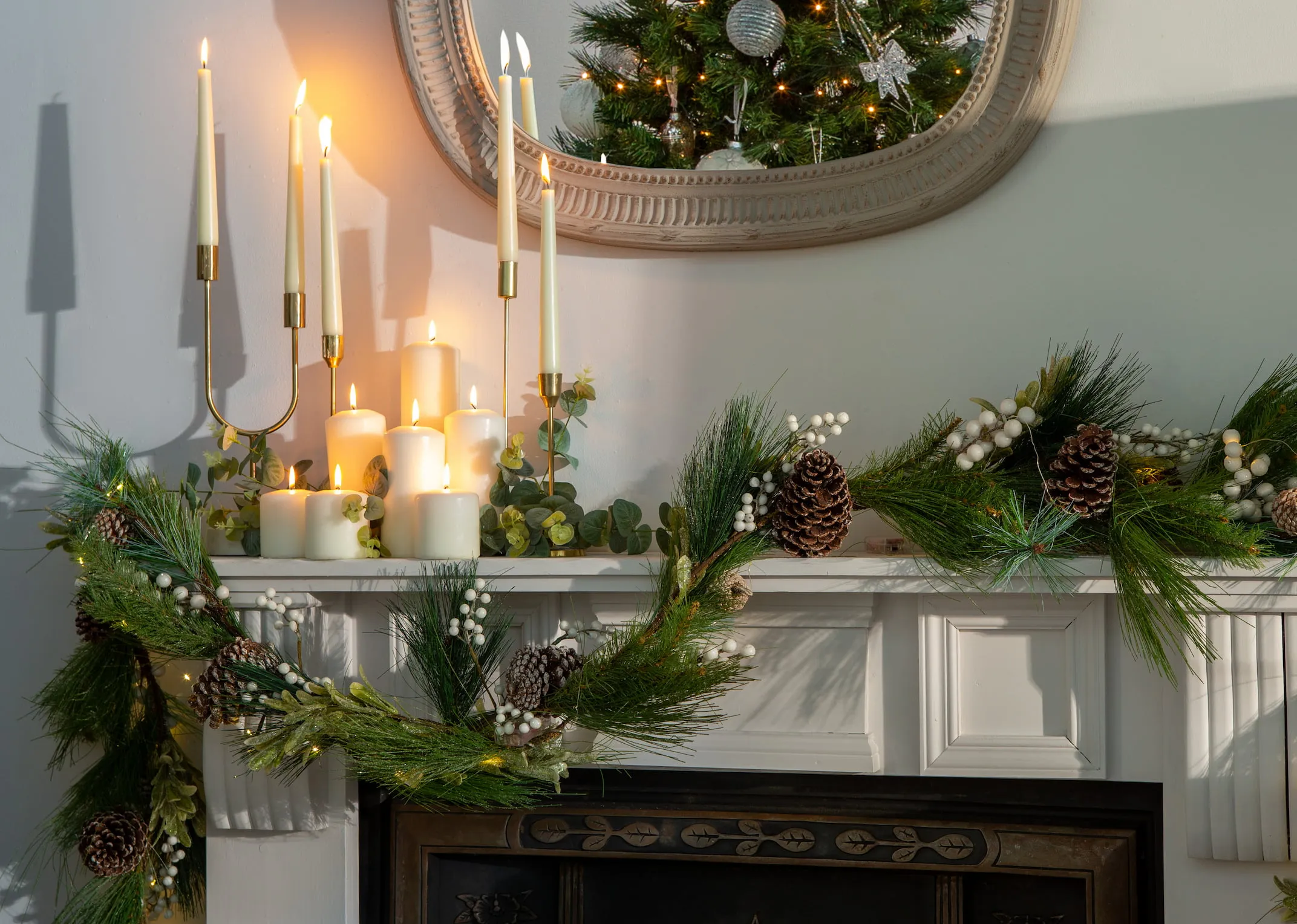 A lifestyle image of a fire mantle dressed with Pearl & pine garland and florike candle holders