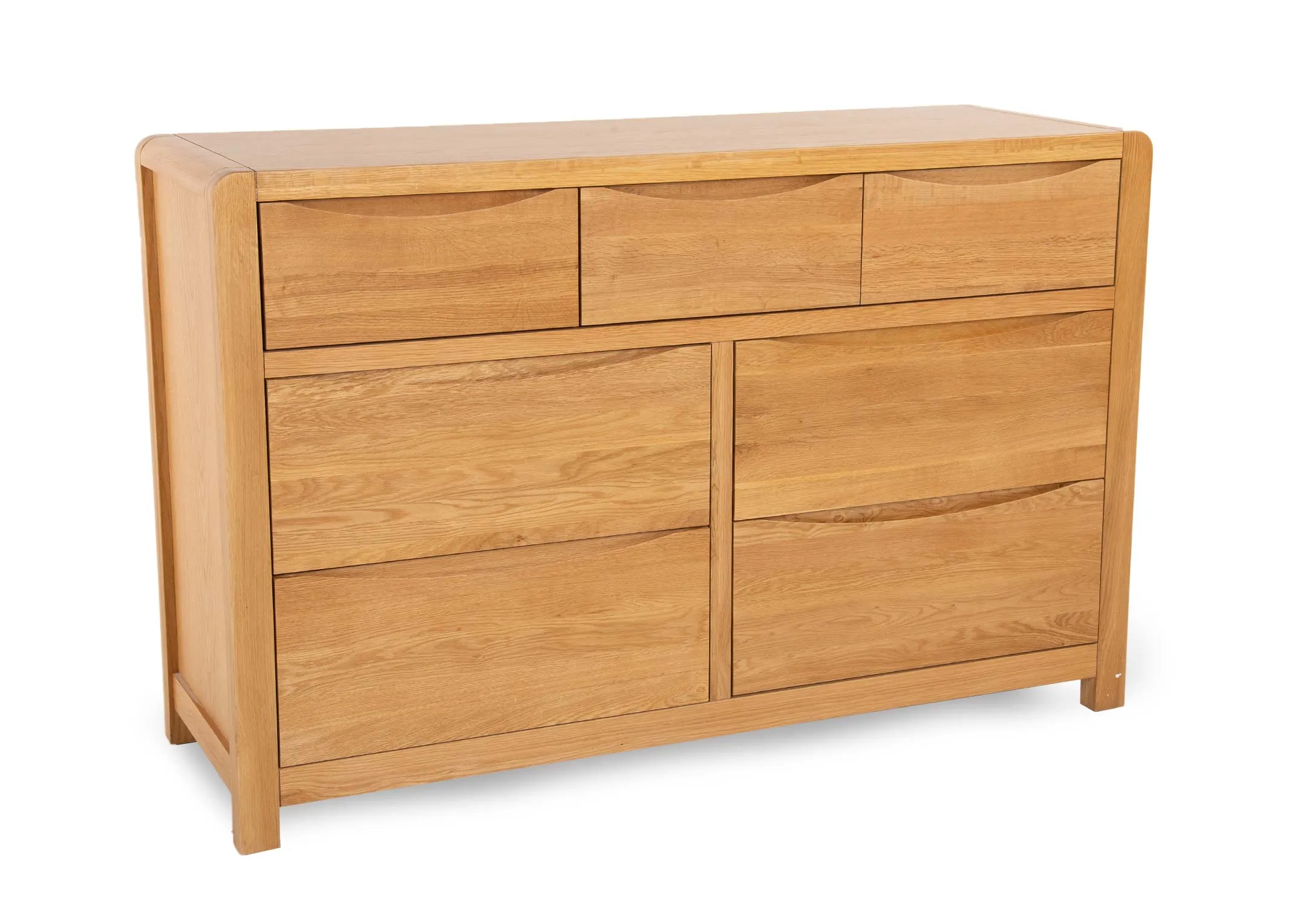 An oak chest of 7 drawers from EZ Livings Iris range. Angled view of smooth texture finish & curved soft edges