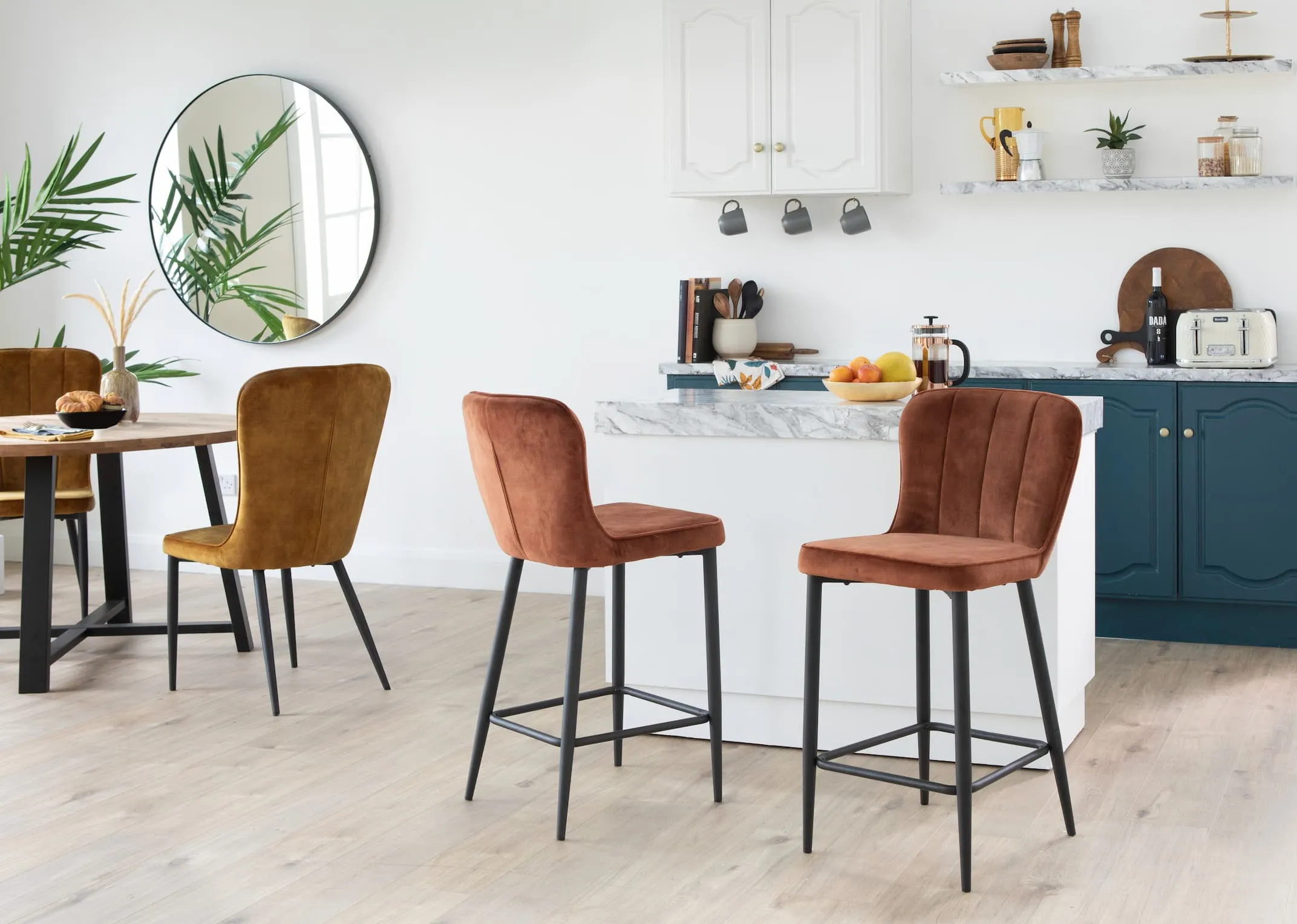A lifestyle image of the Heuston Bar Stools in rust in a kitchen setting with matching dining chairs & renvyle table
