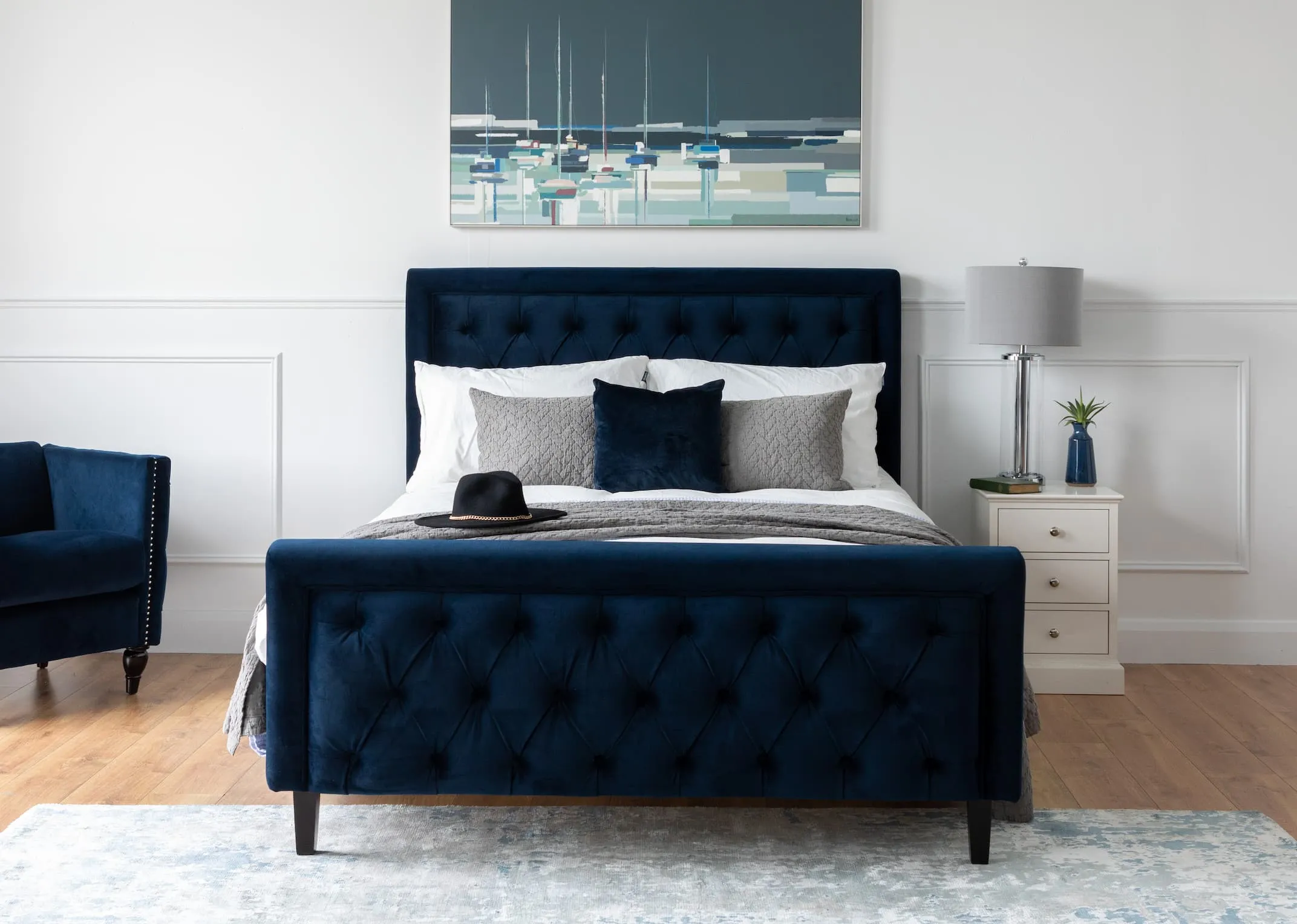 A lifestyle image of the Majestic Blue Velvet bed with armchair & Modesto Silver blue rug.
