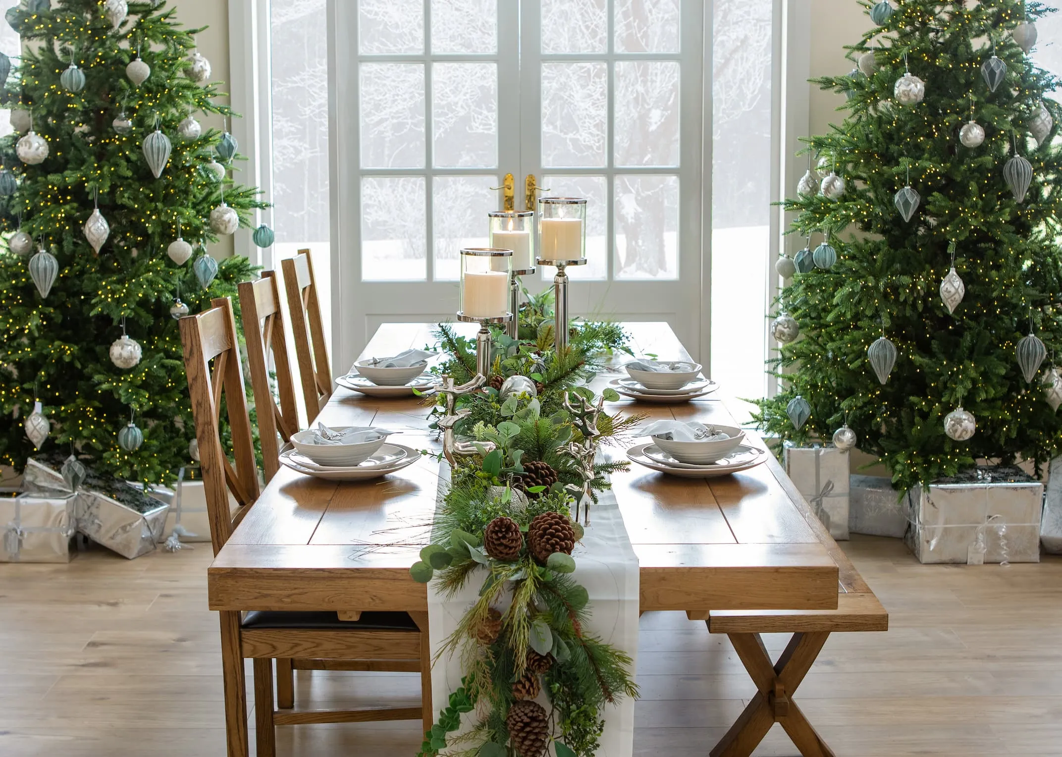 A lifestyle image of the Athens Dining Table with Lush garland & Smooth pillar candle holders in 3 sizes.