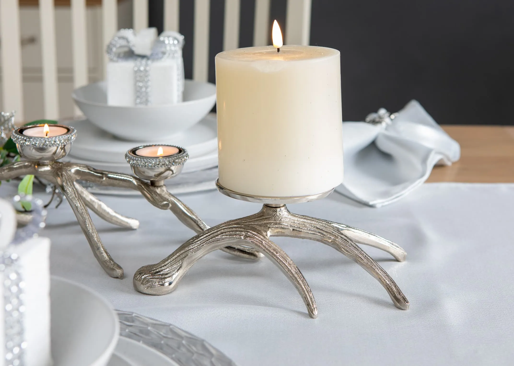 A lifestyle image of the 3 Candle Pillar holder on branch with a silver decor theme on Sonoma table.