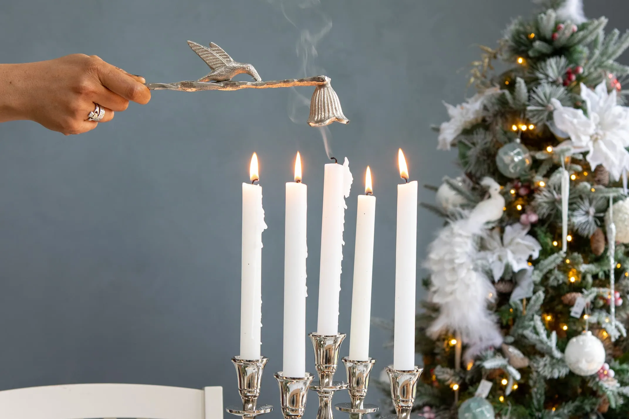 A lifestyle image of the Candle Snuffer with bird quenching cnadles on the 5 stick candleholder