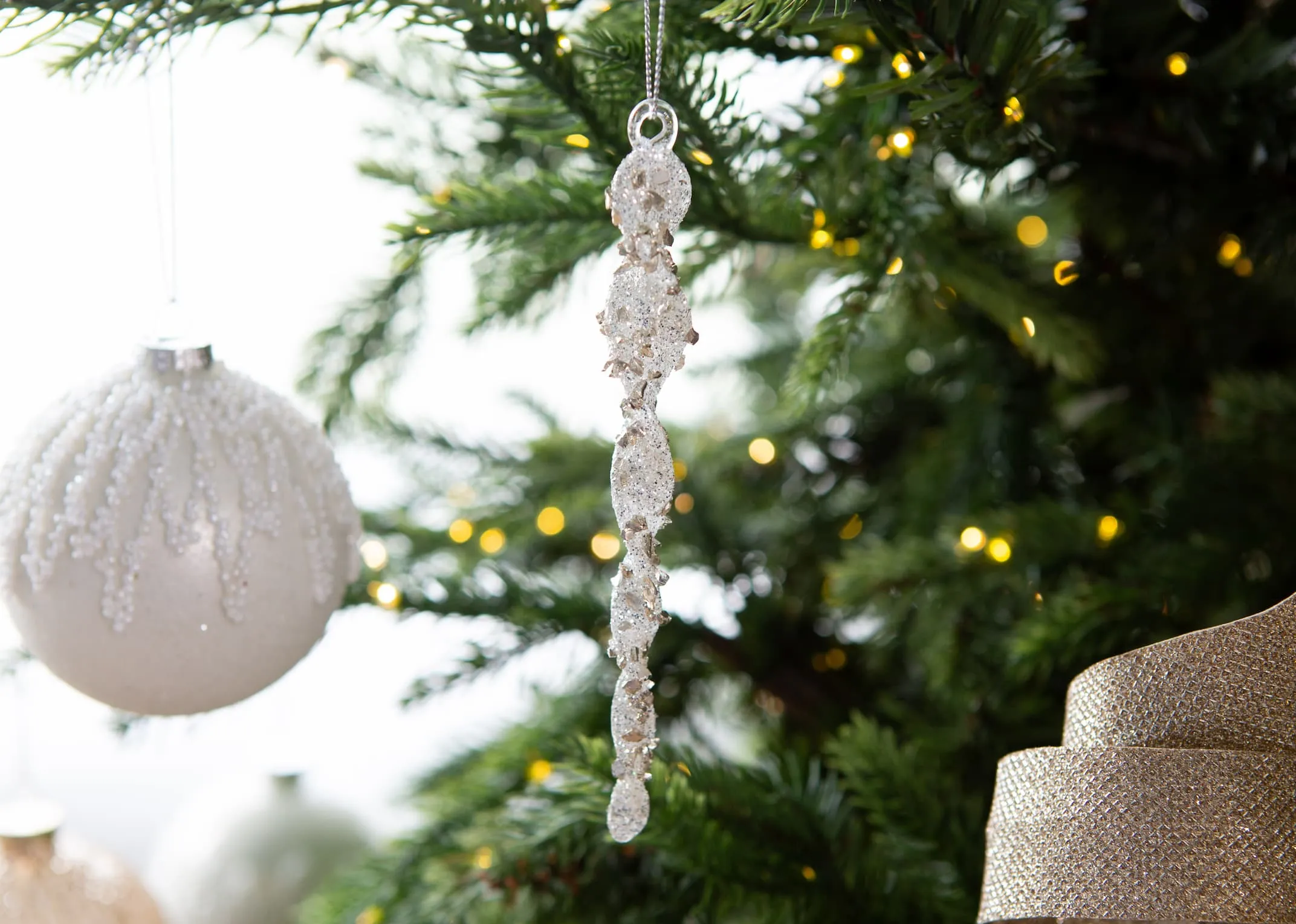 A lifestyle image of the Small Silver glitter icicle on an EZ Living Furniture tree
