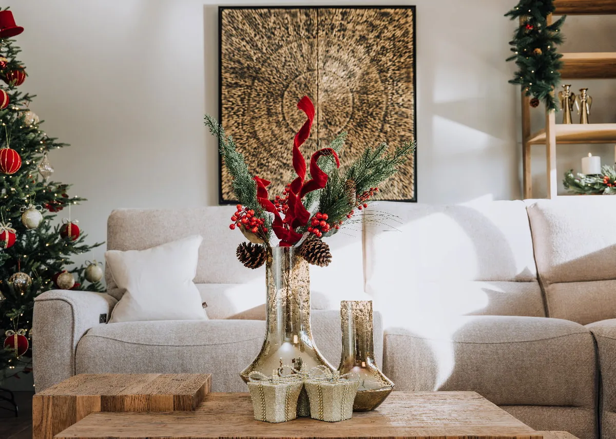 A lifestyle image of the Ashbrook sofa with Nova coffee table with vase of red velvet spray berries and pine.