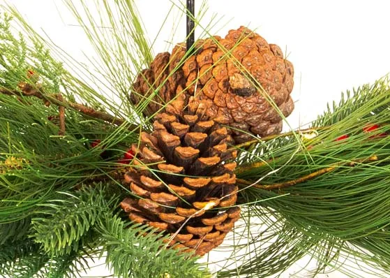 A berry & pine cone garland covered candle holder from EZ Livings Christmas range. Closeup of pine cones