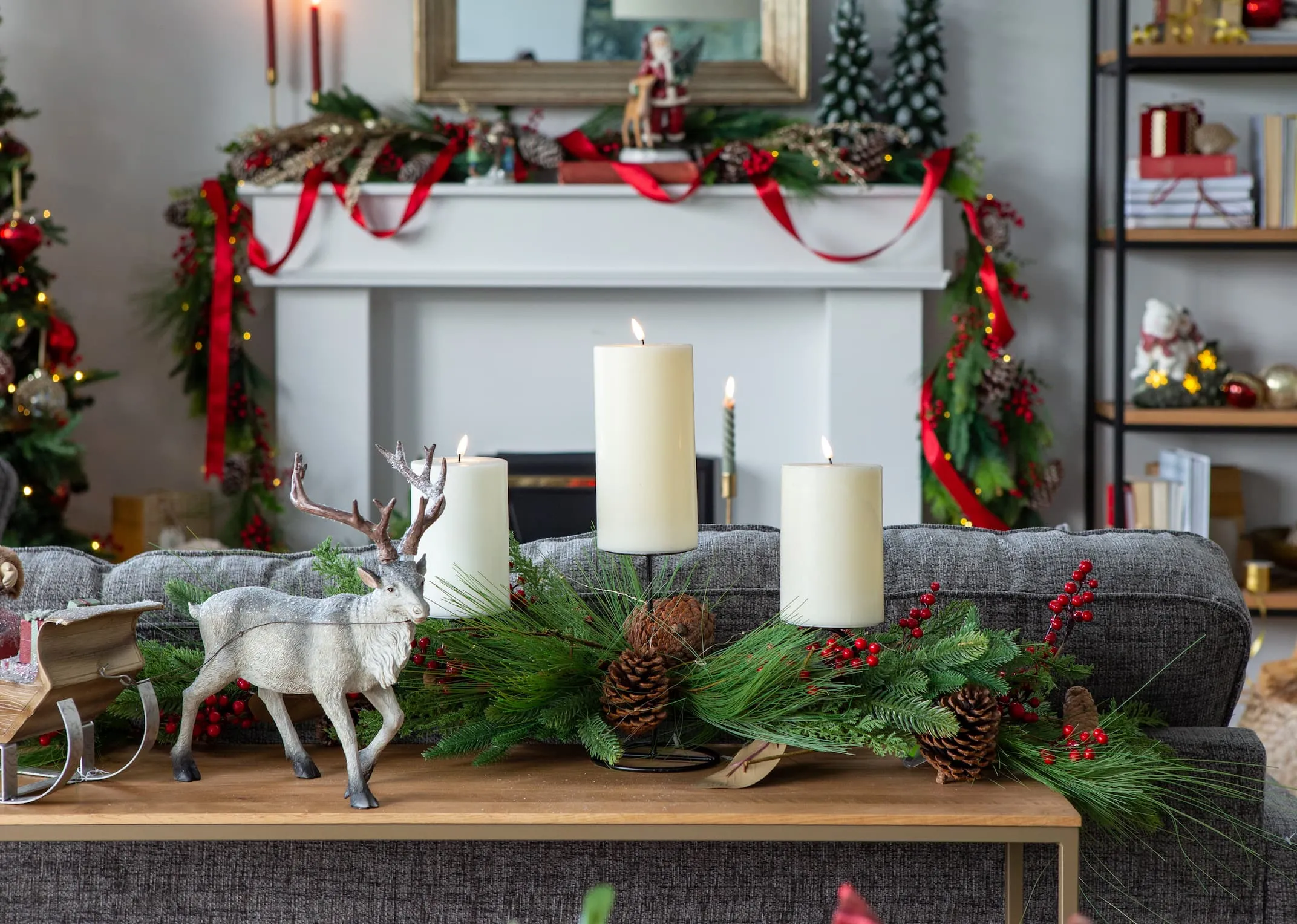 A lifestyle image of the Berry & Pine Candleholder on the Aston console table with the Reindeer pulling Santa figurine.