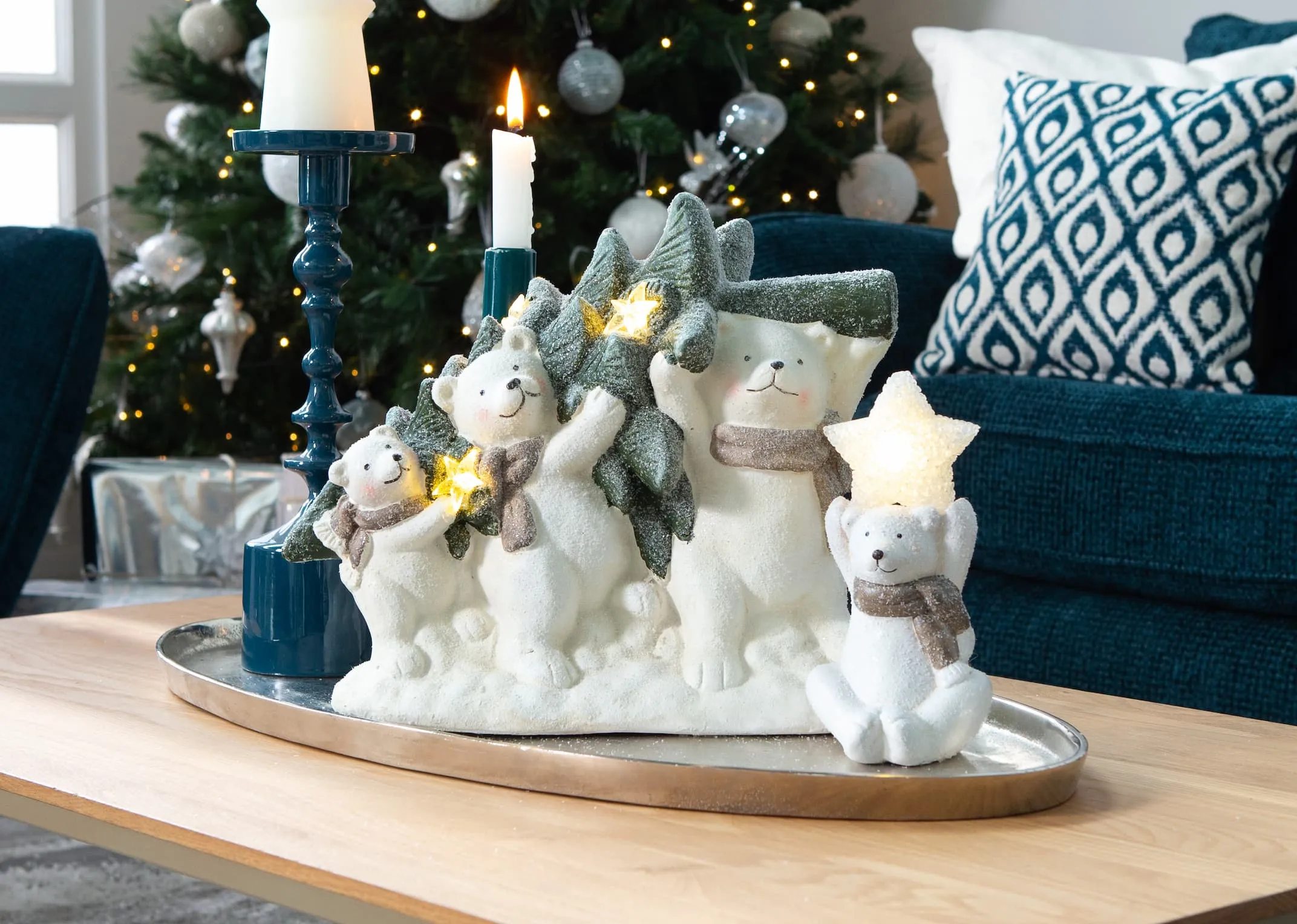 A lifestyle image of the bears carrying a Christmas tree on a coffee table with sheva candle holders.