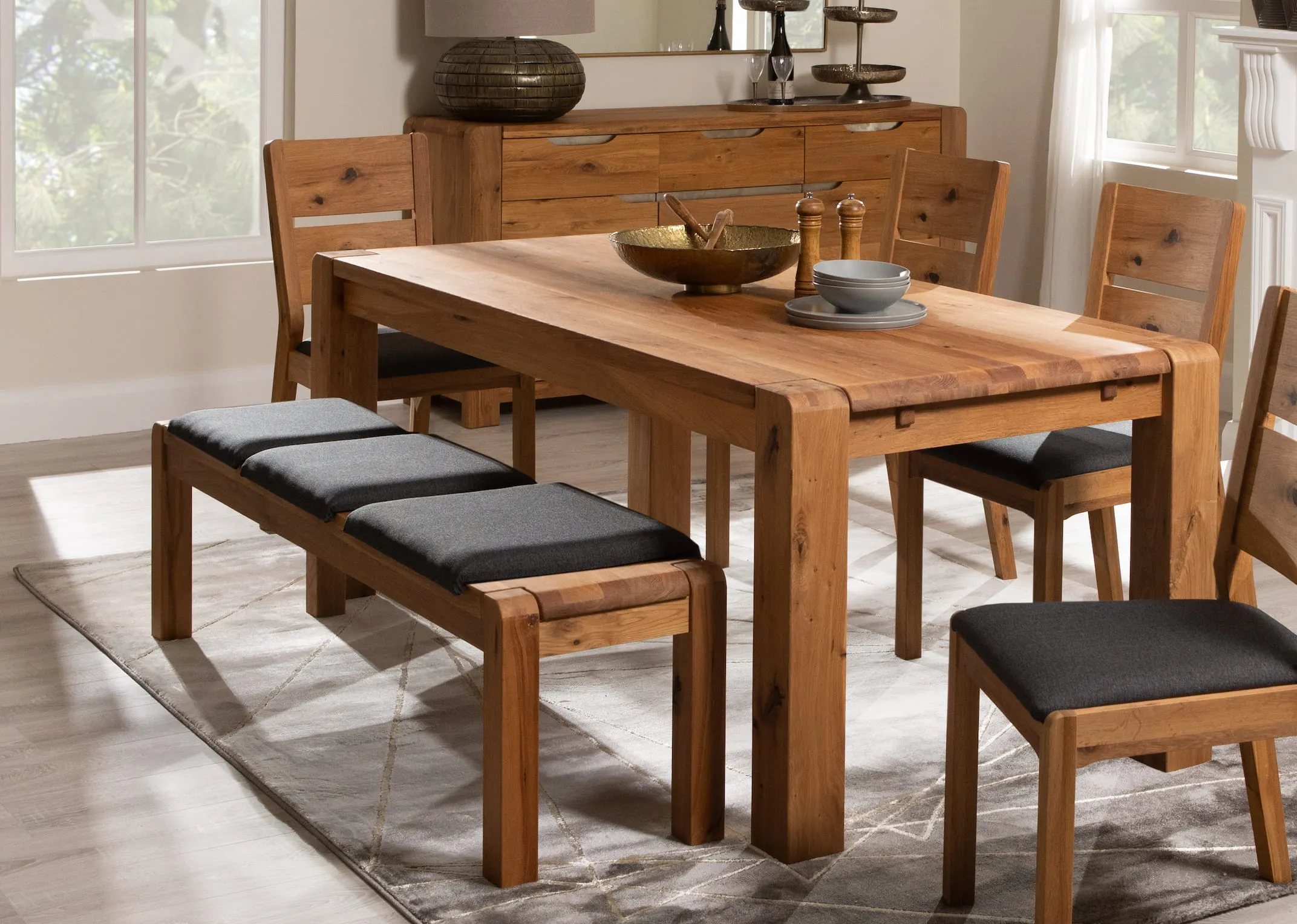 A lifestyle image of the Como dining range with table and bench with 3 seat pads and a matching dining chairs