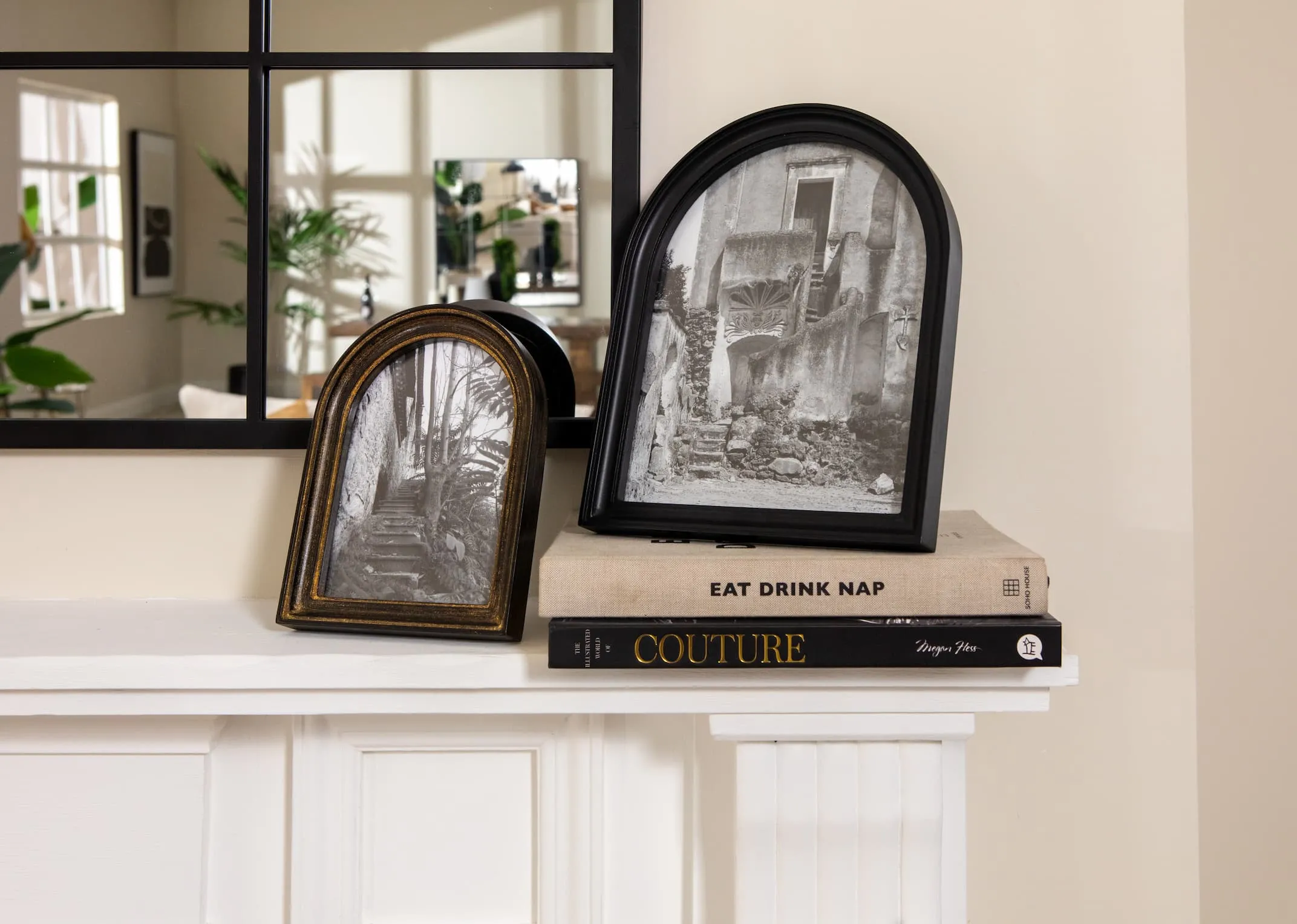 A lifestyle image of the Letta photo frames in brass and black on books on a mantle.