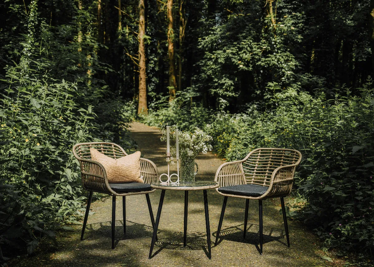 A bistro set with 2 wicker chairs and a small glass table from EZ Livings Menorca range. Sida view of rattan frame and metal legs