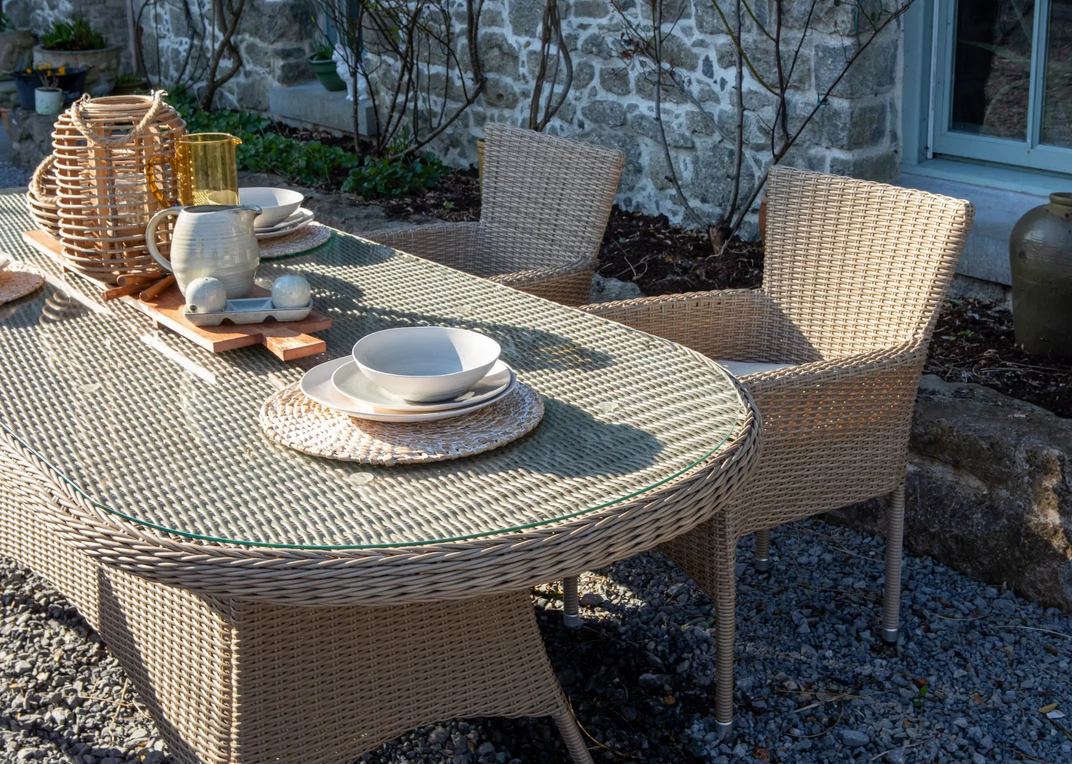 image of the Seville Oval table with garden dining chairs in a house garden setting.