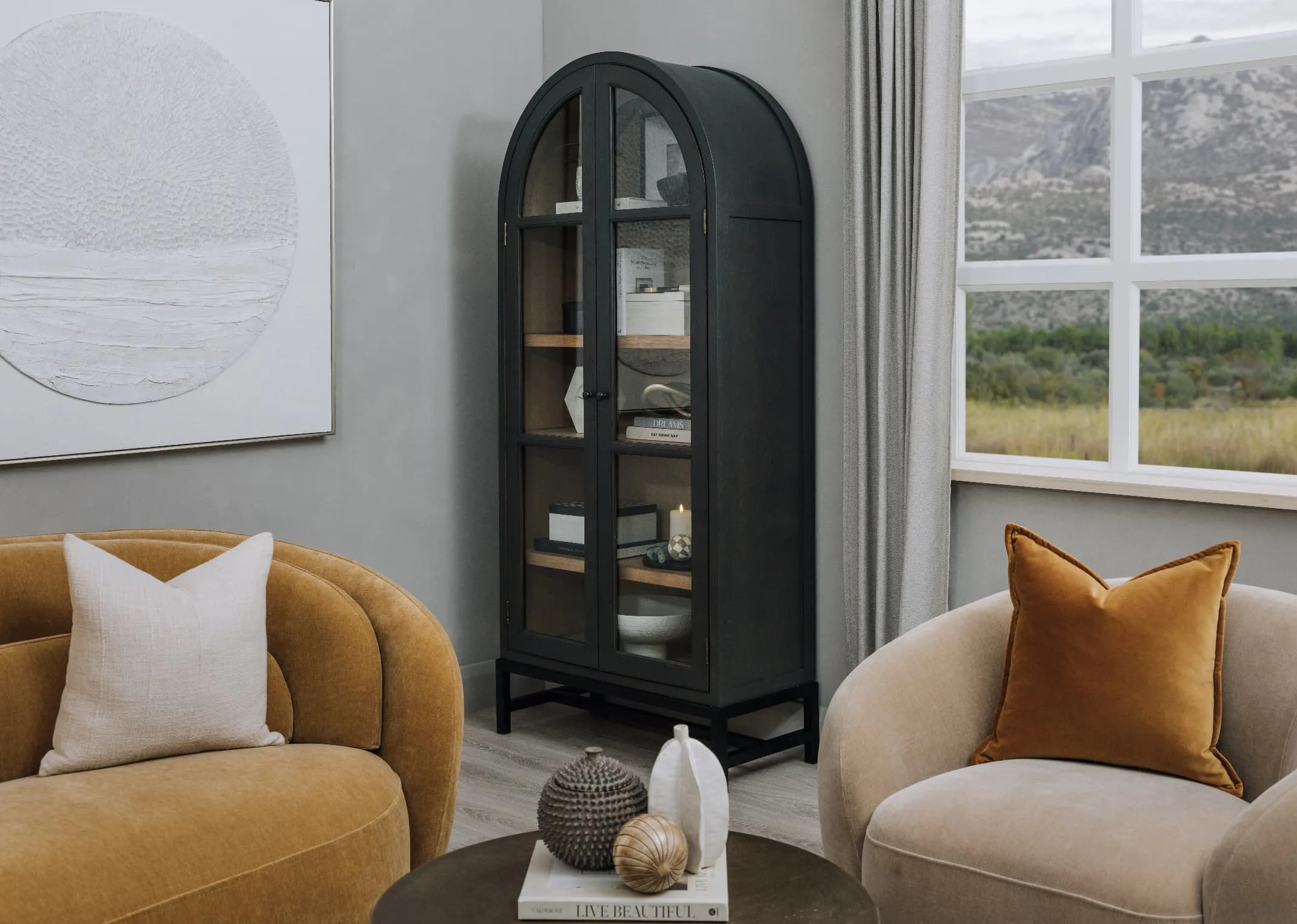 A lifetsyle image of the Danica Sand swivel with gold cushion with Juliet cabinet