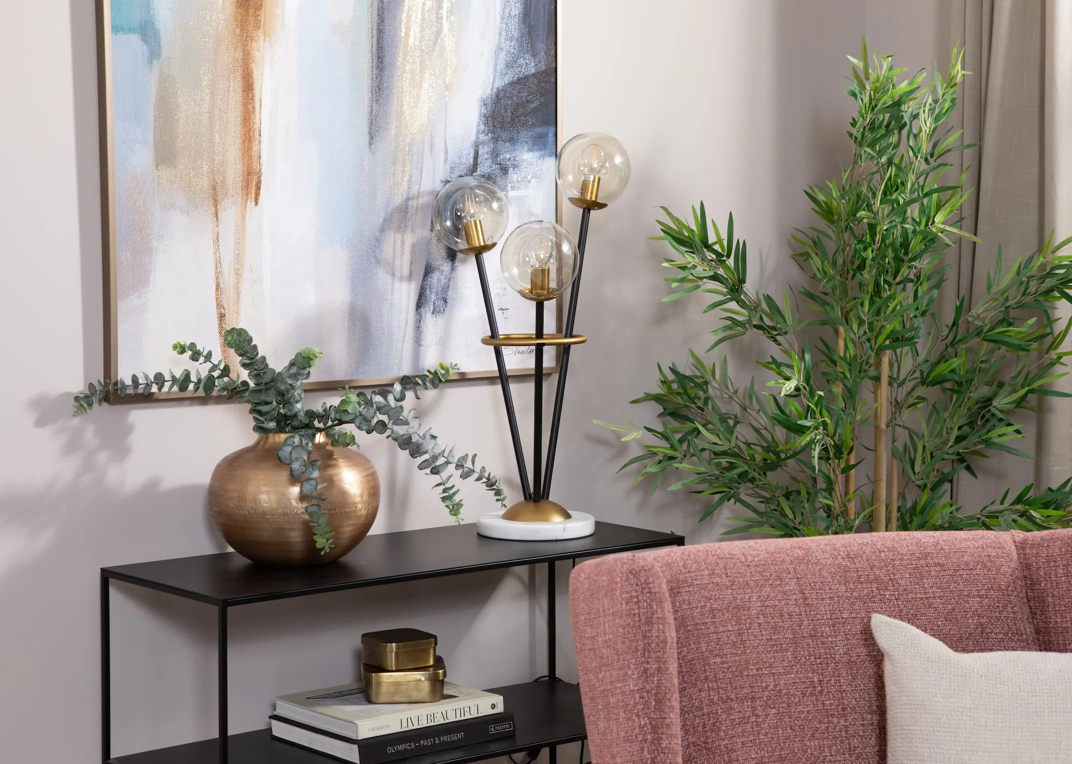 A metal table lamp with 3 round bulbs from EZ Livings Ortez range. Closeup of white marble round base