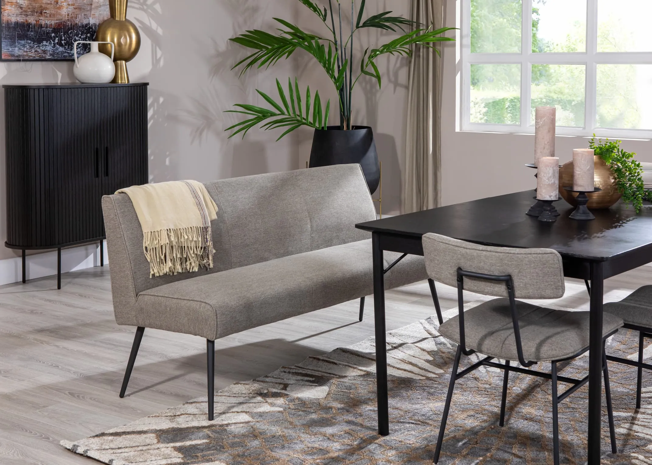 A lifestyle image of the Savona rectangular table with Decker grey fabric bench & chairs and pasha rug with nola cabinet.