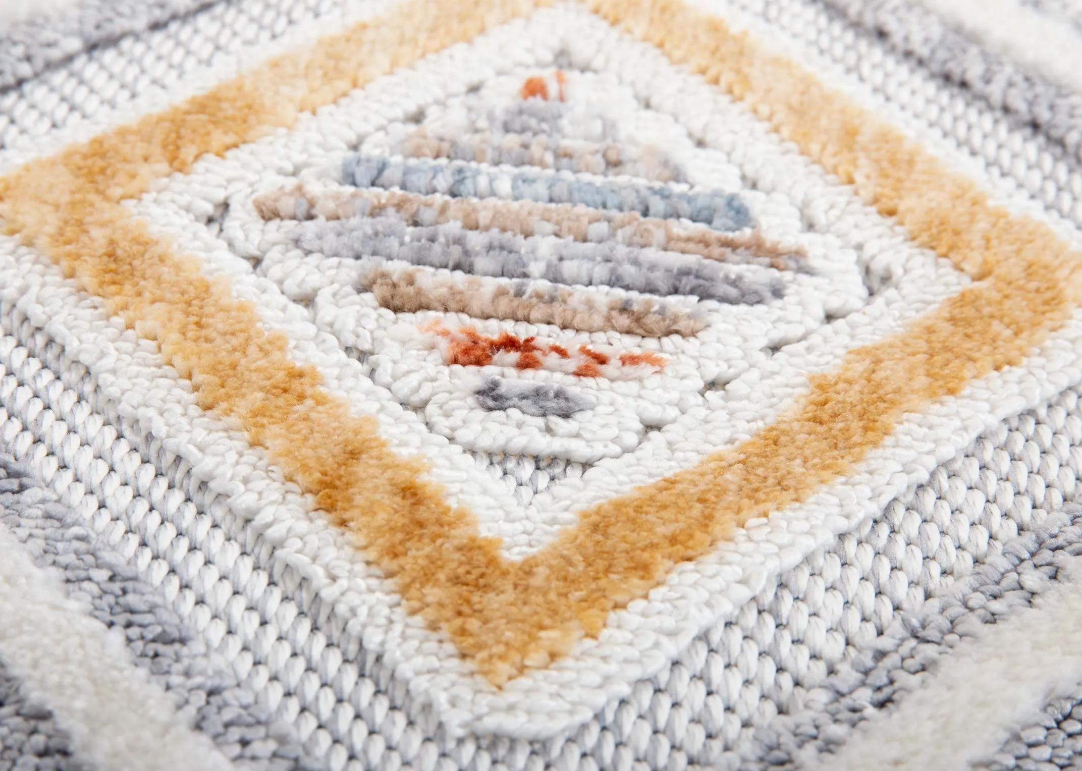 A white medium rug with red gold yellow and blue geometric design from EZ Livings Holiday range. Closeup of yellow traingle print