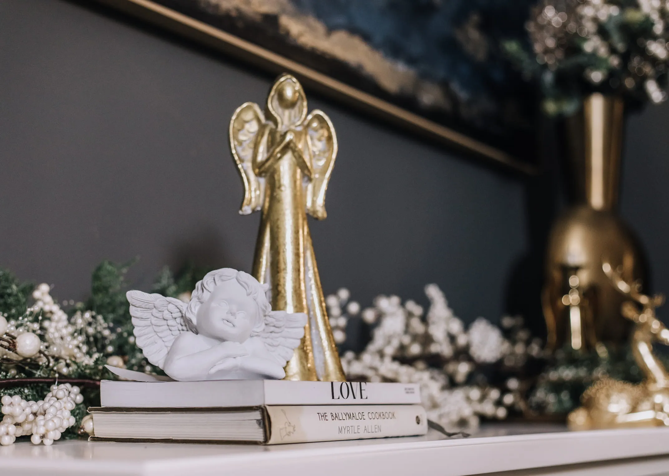 A lifestyle image of a mantle with pearl garland and white angel ornament.