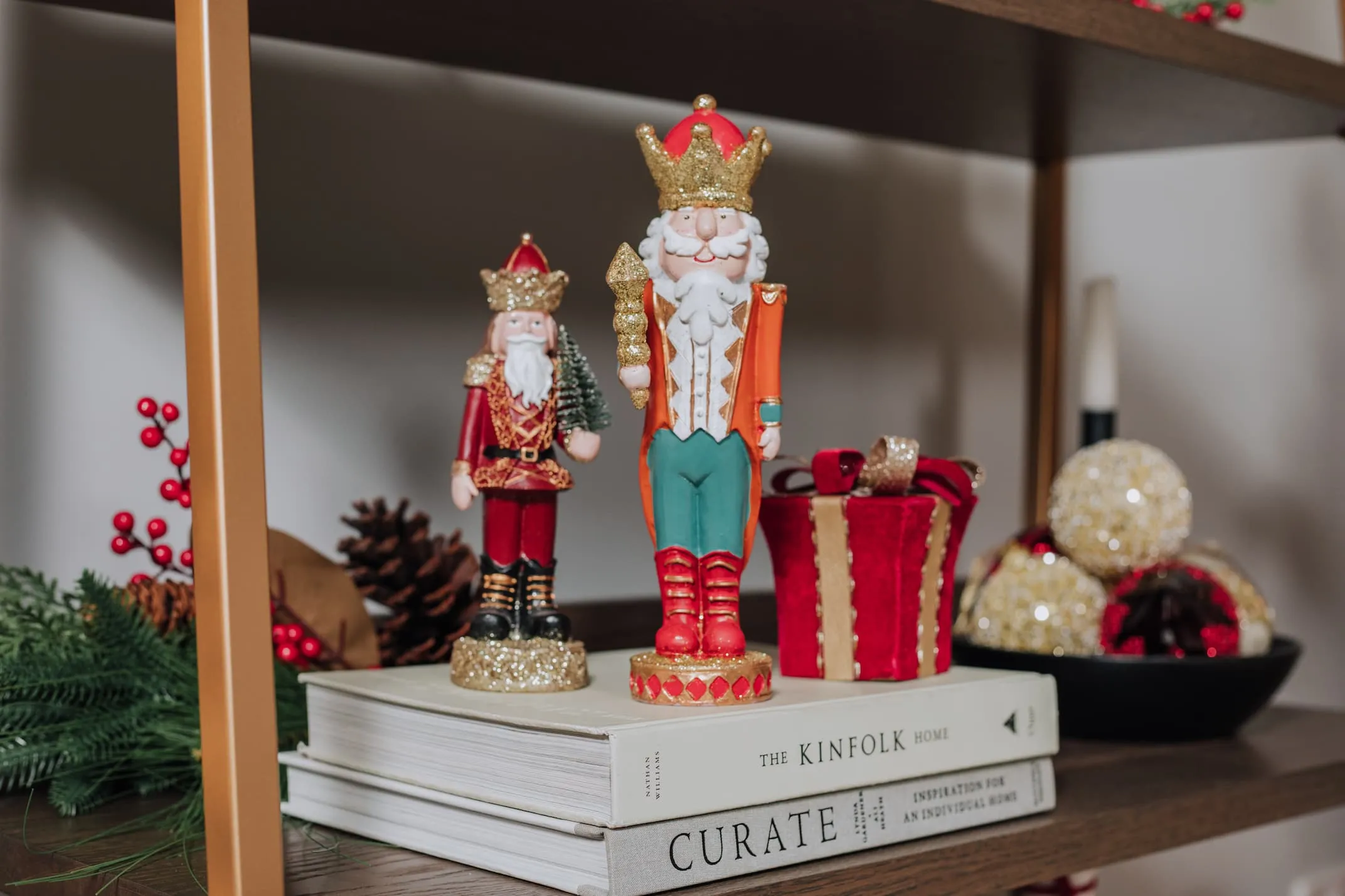 A lifestyle image of a bookshelf with Nutcracker with torch & holding tree and a red & gold gift box