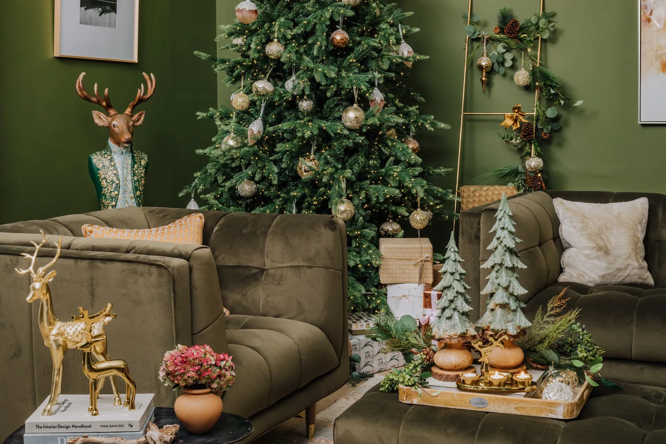 A lifestyle image with the Grace Sofa and Rockefeller tree with a range of Gold deer ornaments & Wooden trees.
