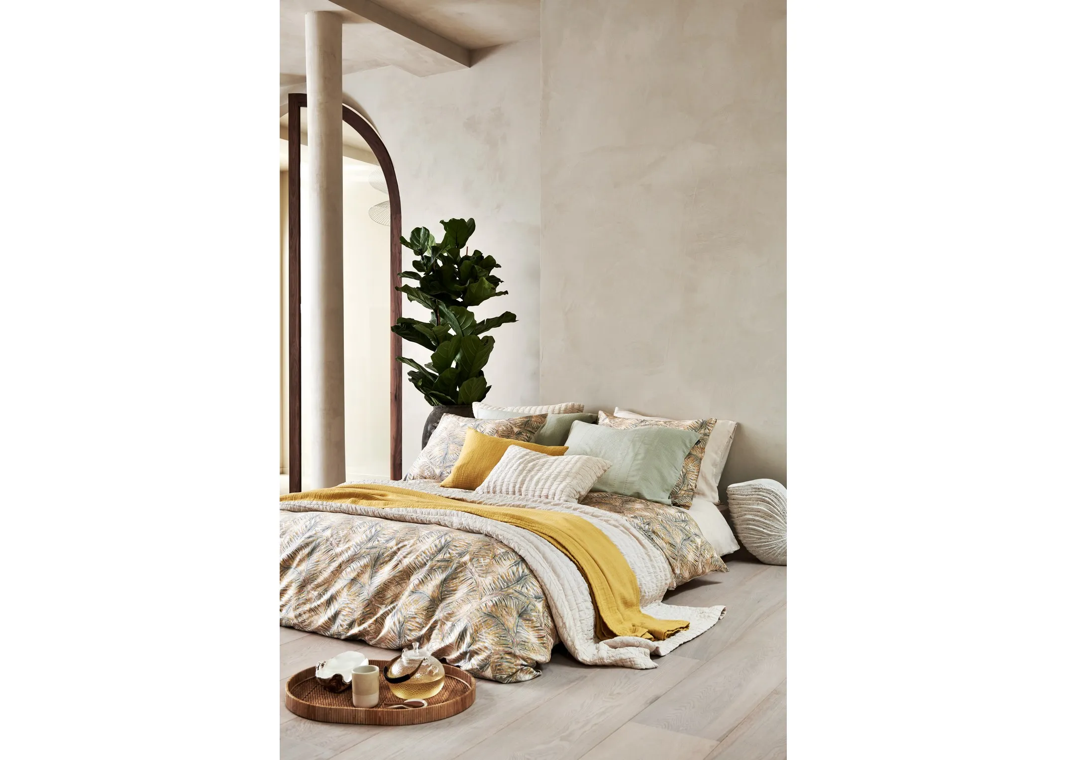 A lifetsyle image of a room with high ceilings with a floor bed dressed in Van Dyck bedding including Multi bedlinen.