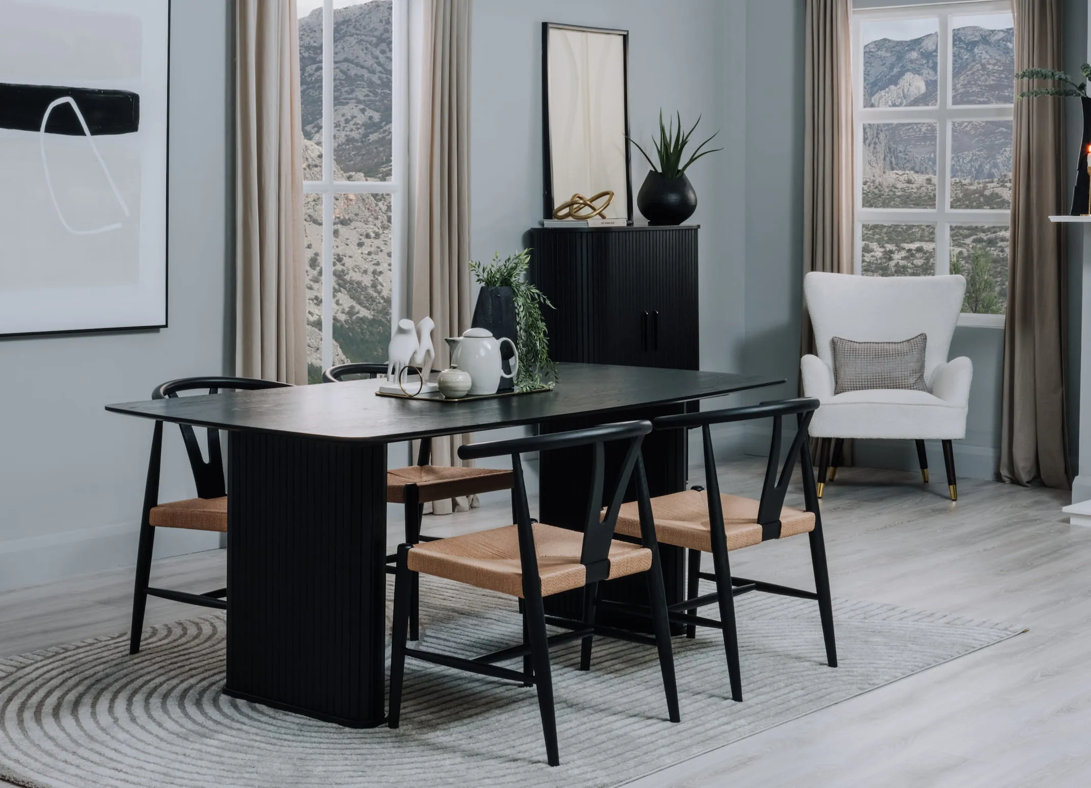 A lifestyle image of the Nola black table with Cape chairs with Eli rug.