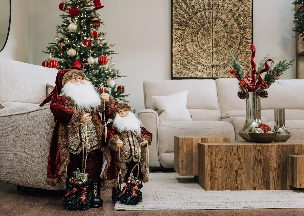 A lifetsyle image of the 2 Mr Claus figurines with a red themed Christmas tree and Nova coffee table.