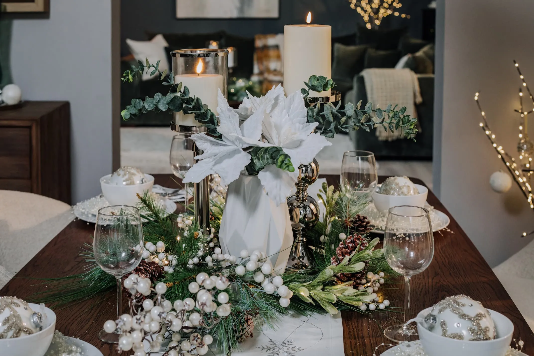 A lifestyle image of the Whiet Poinsettias in a vase with Silver Pillar Candle Stand.