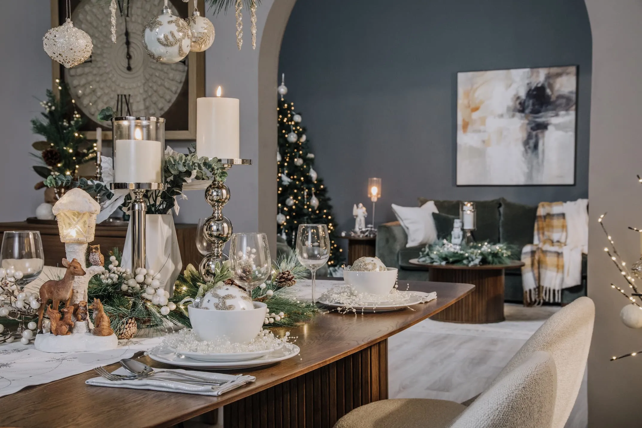 A lifestyle image of the Nola dining table with Silver Pillar Candle Stands and pearl and pine accessories.