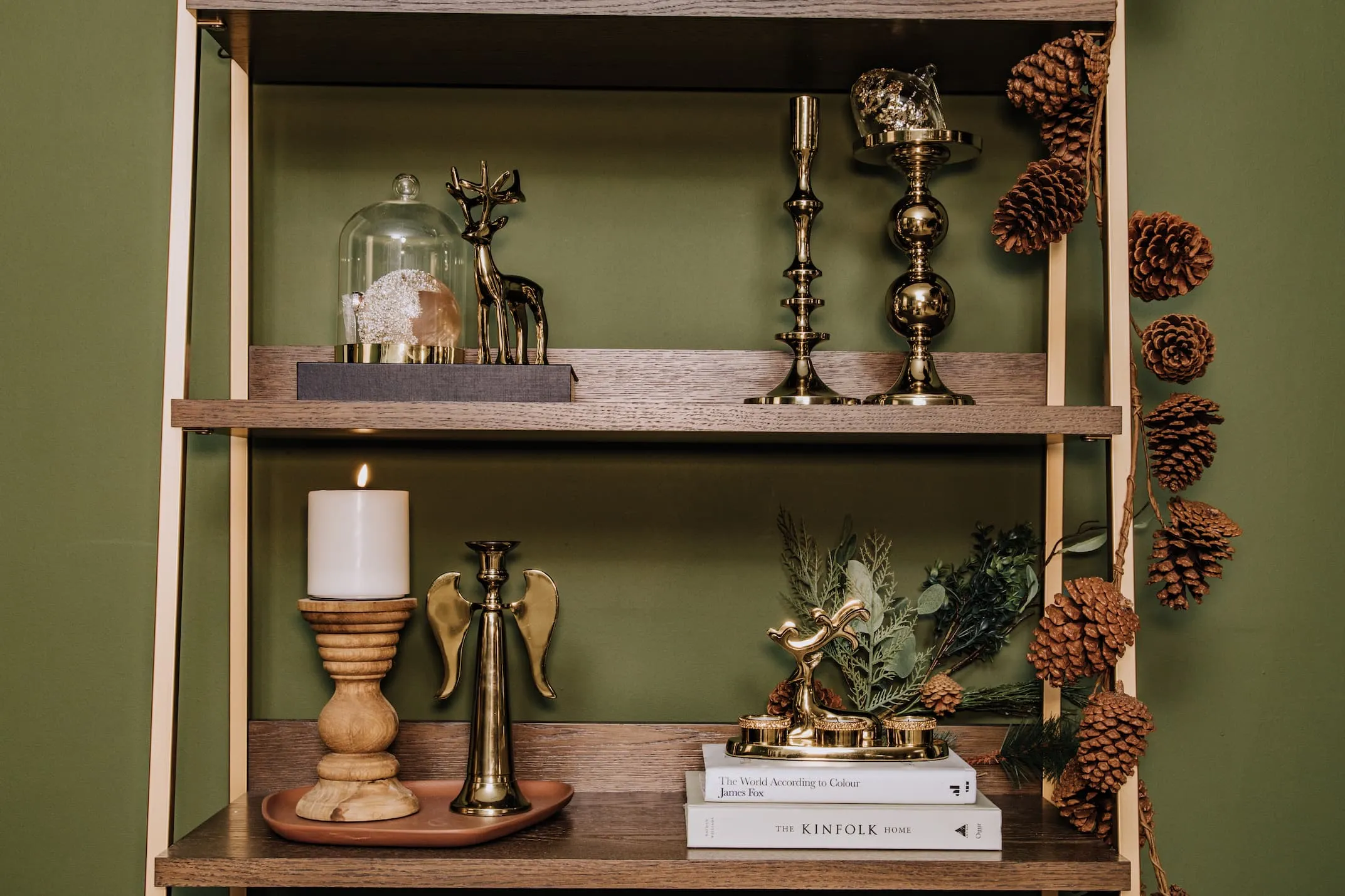 A lifestyle image of the Greenwich bookcase with gold angel candleholder with deer and tlights with pillar candle holders.