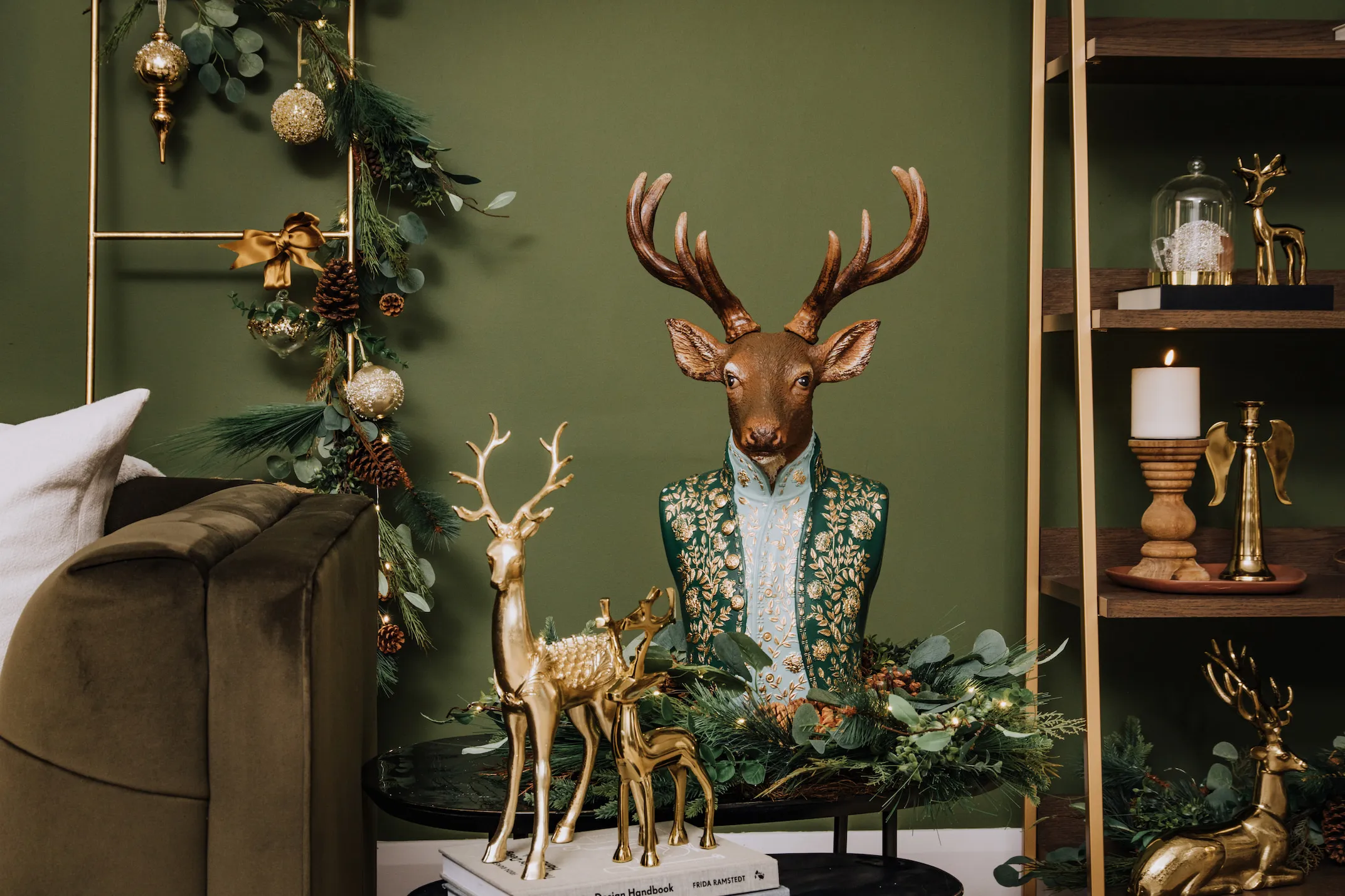 A lifestyle image of the Stag and gold deers with the Angel candle holder on the Greenwich bookcase.