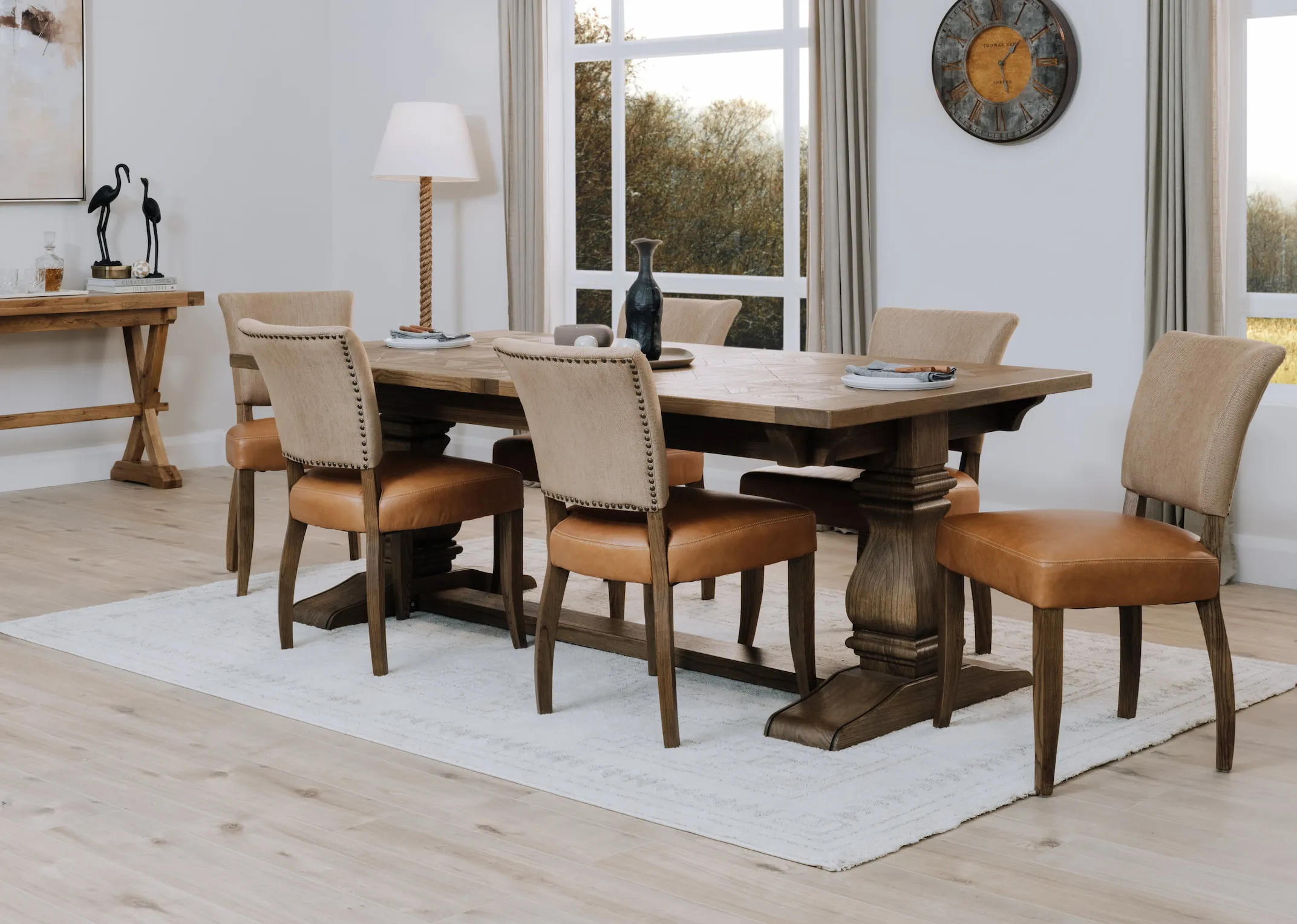 A lifestyle image of the Biarritz dining tablke and tan leather dining chairs with Pier floor lamp.