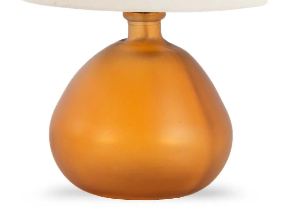 A round orange glass table lamp with off white shade fro EZ livings Alabama range.Closeup of amber glass base