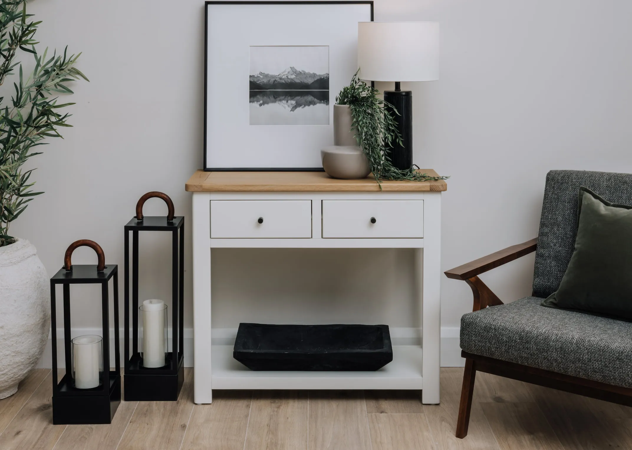 A lifestyle image of the Barleycove console table with lamp and 2 black lanterns.