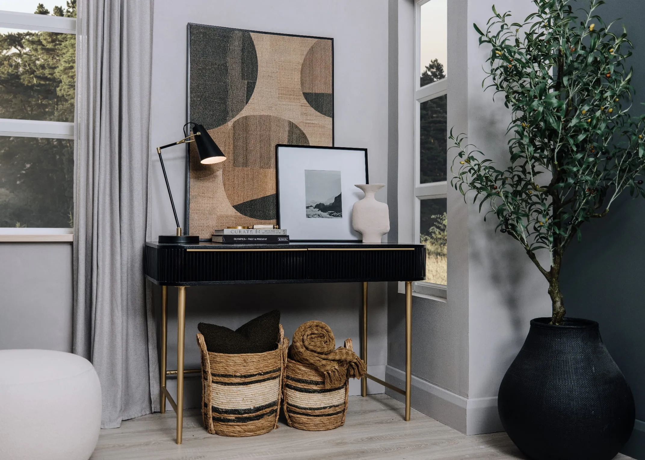A lifestyle image of the Rego Console Table with canvas and frames and table lamp and baskets underneath.