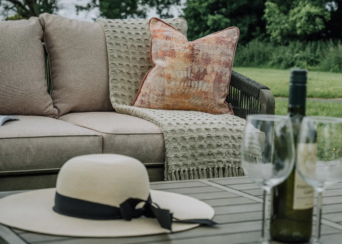 An outdoor lounge set with a 2 seater sofa a table and 2 chairs from EZ Livings Monpellier range. Angled view of low slatted grey acacia table.