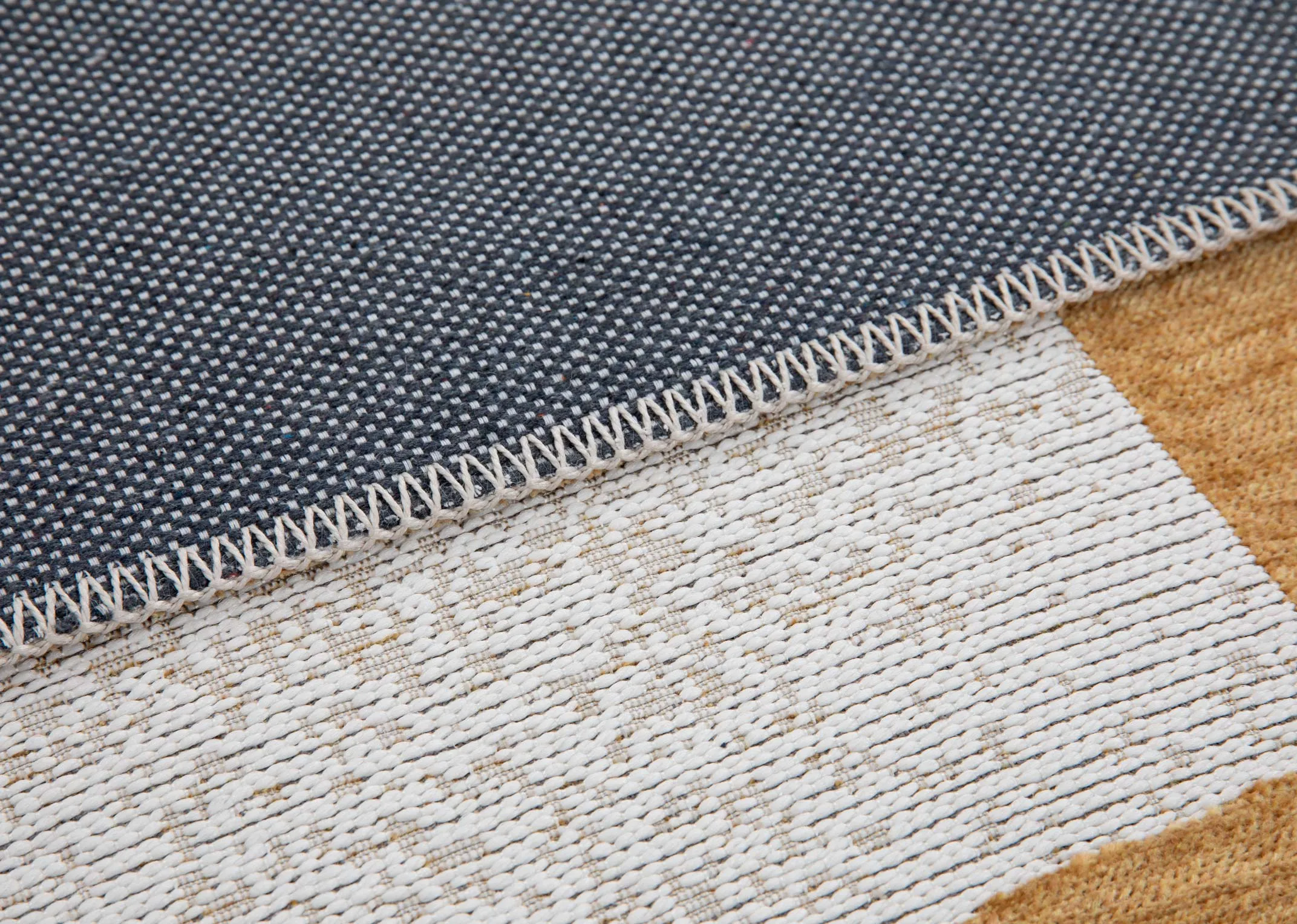 A gold and grey abstract print rug from EZ Livings Chace range. Closeup of navy underlay