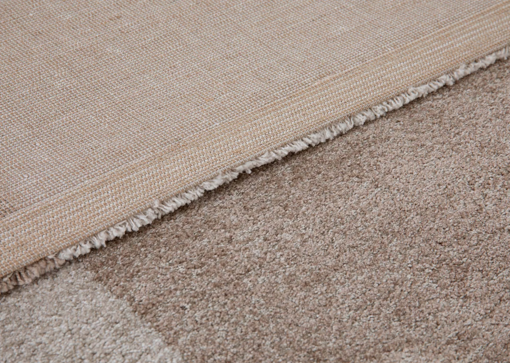 A beige brown grey and orange geo shaped rug from EZ Livings Divine range. Closeup of underlay and short pile