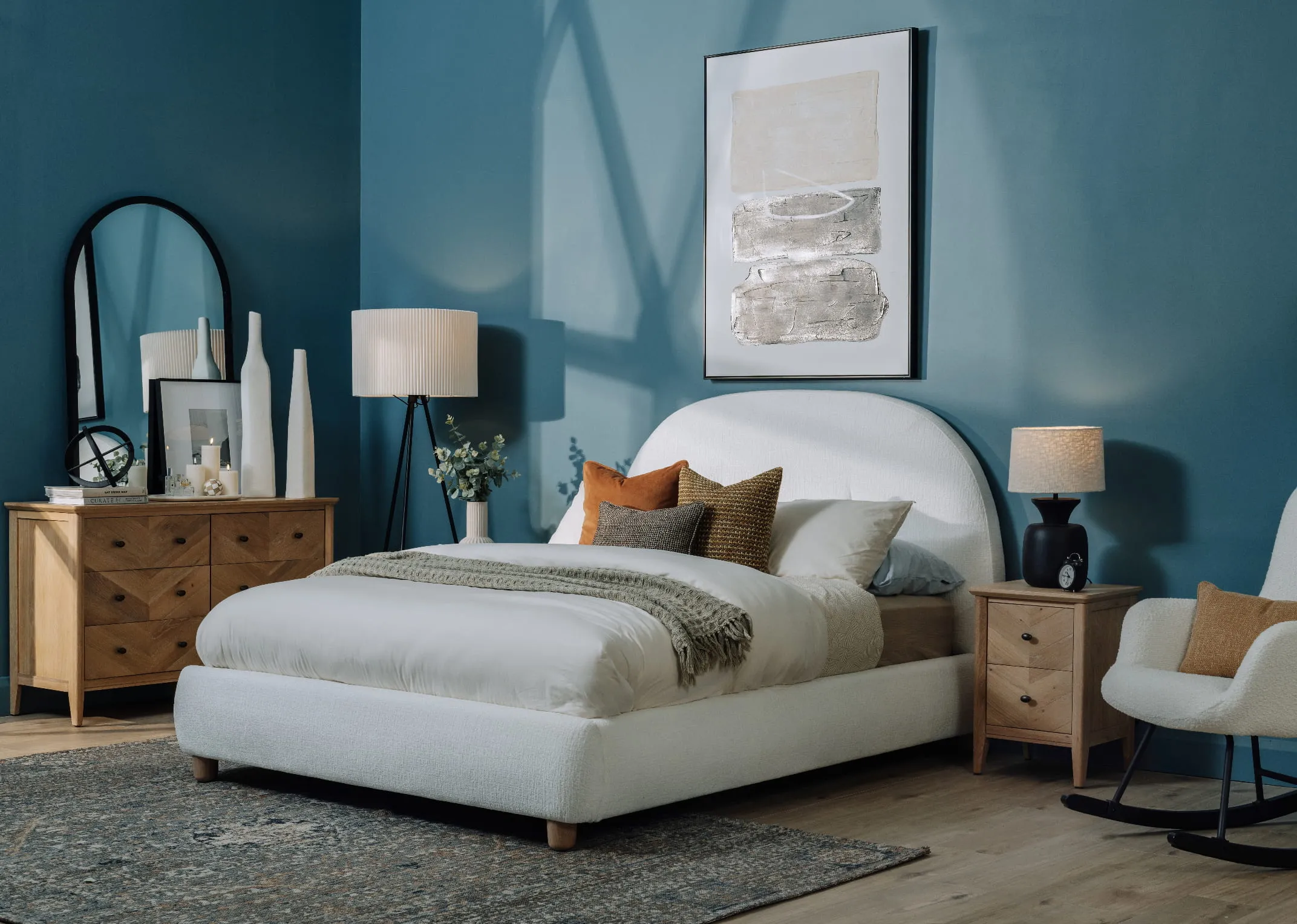 A lifestyle image of the Joelle white bedframe with chevron oak locker and chest with a blue bedroom and Maxima rug.